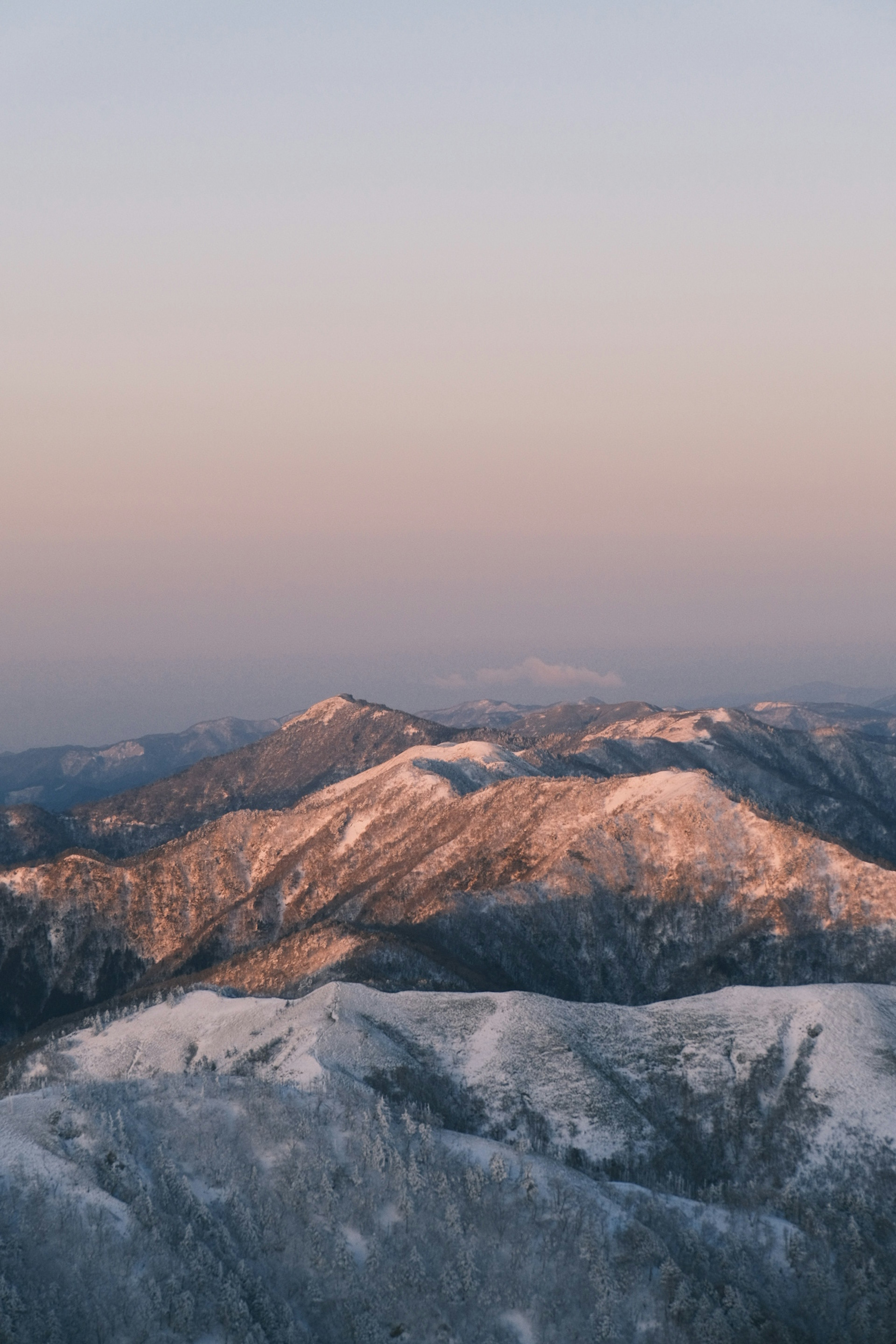 Montañas cubiertas de nieve bajo un suave cielo crepuscular