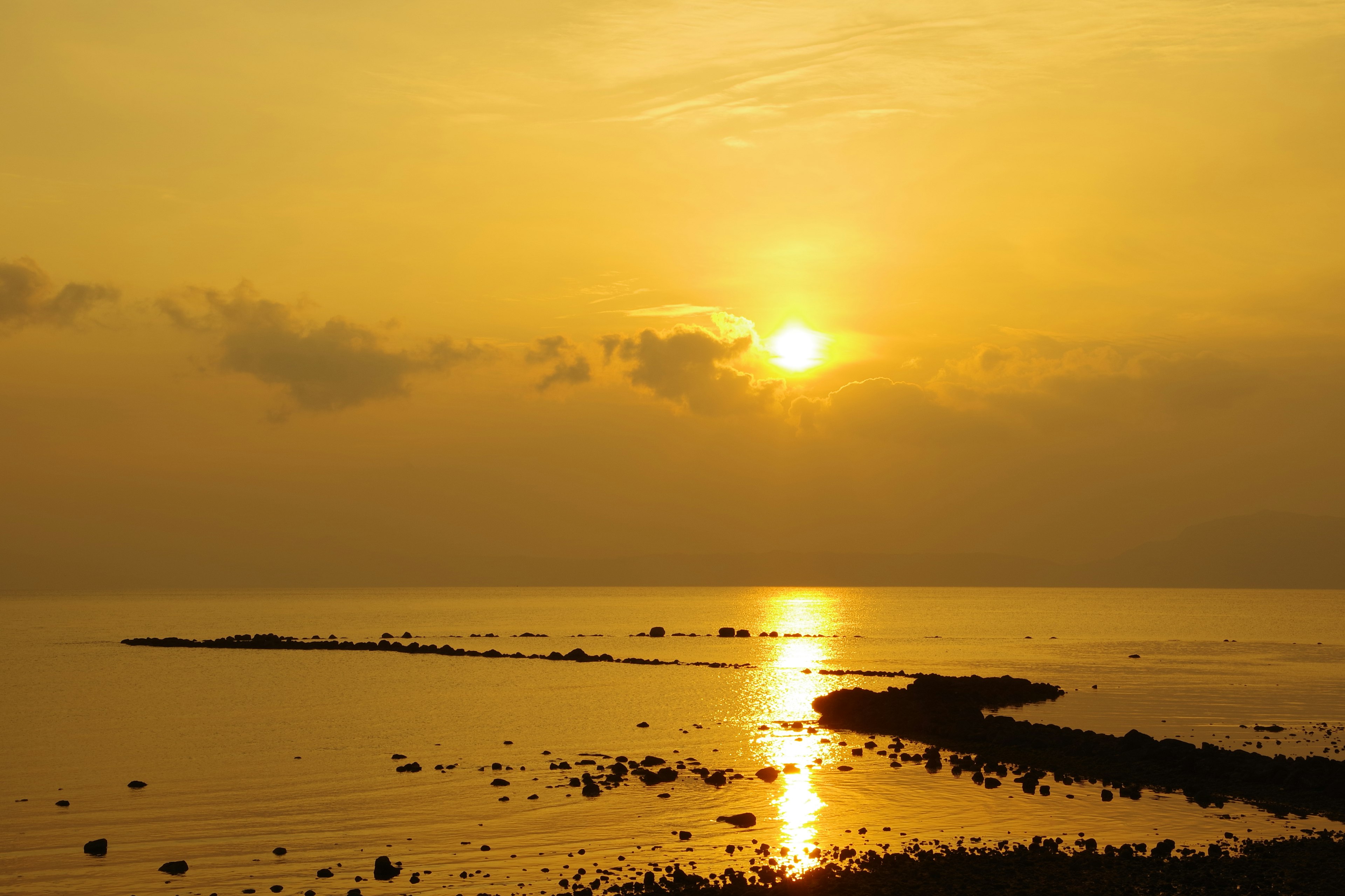 Pemandangan senja dengan matahari terbenam yang memantul di laut