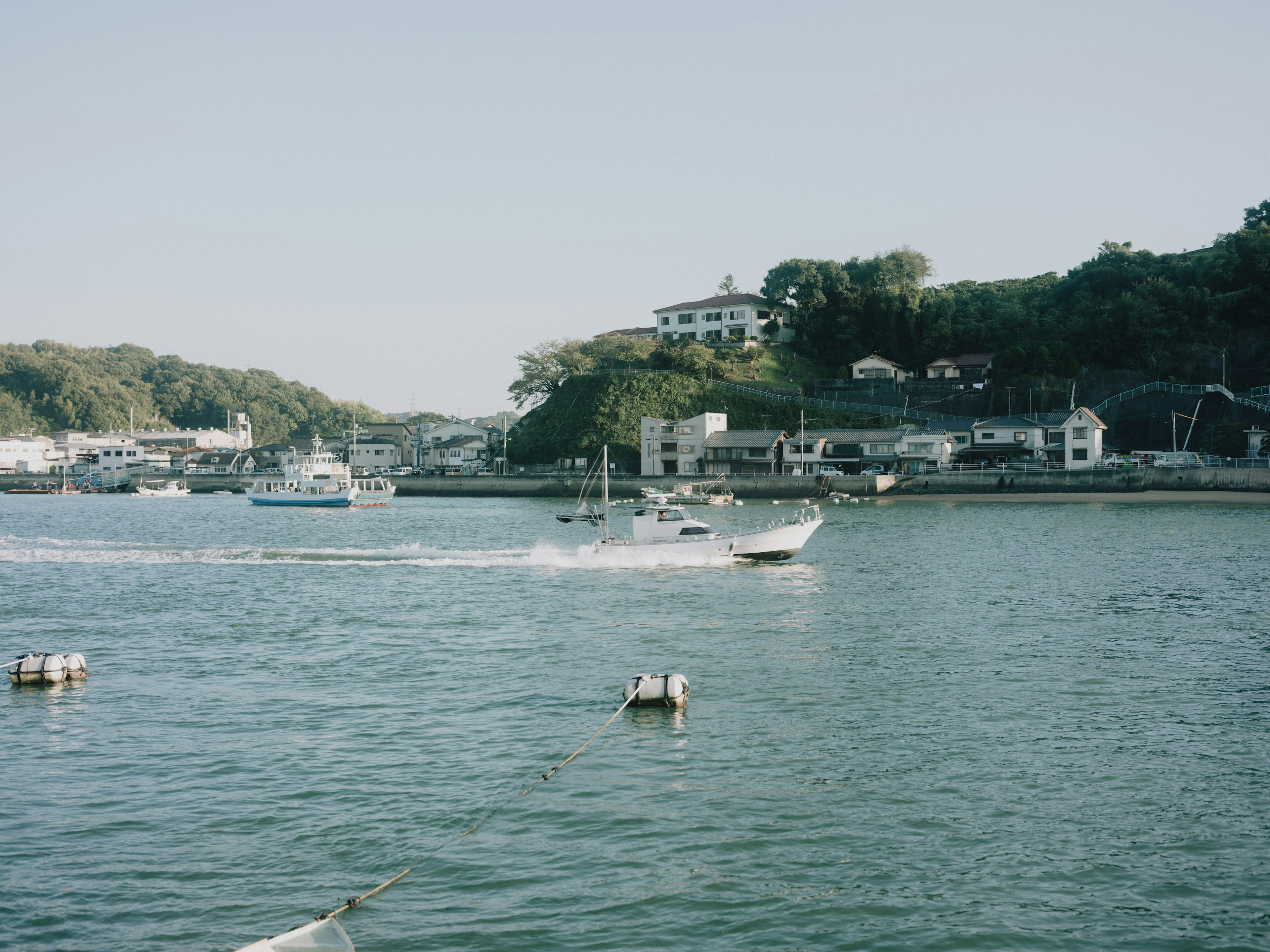 Scenic view of a boat cruising on calm waters with a harbor town in the background