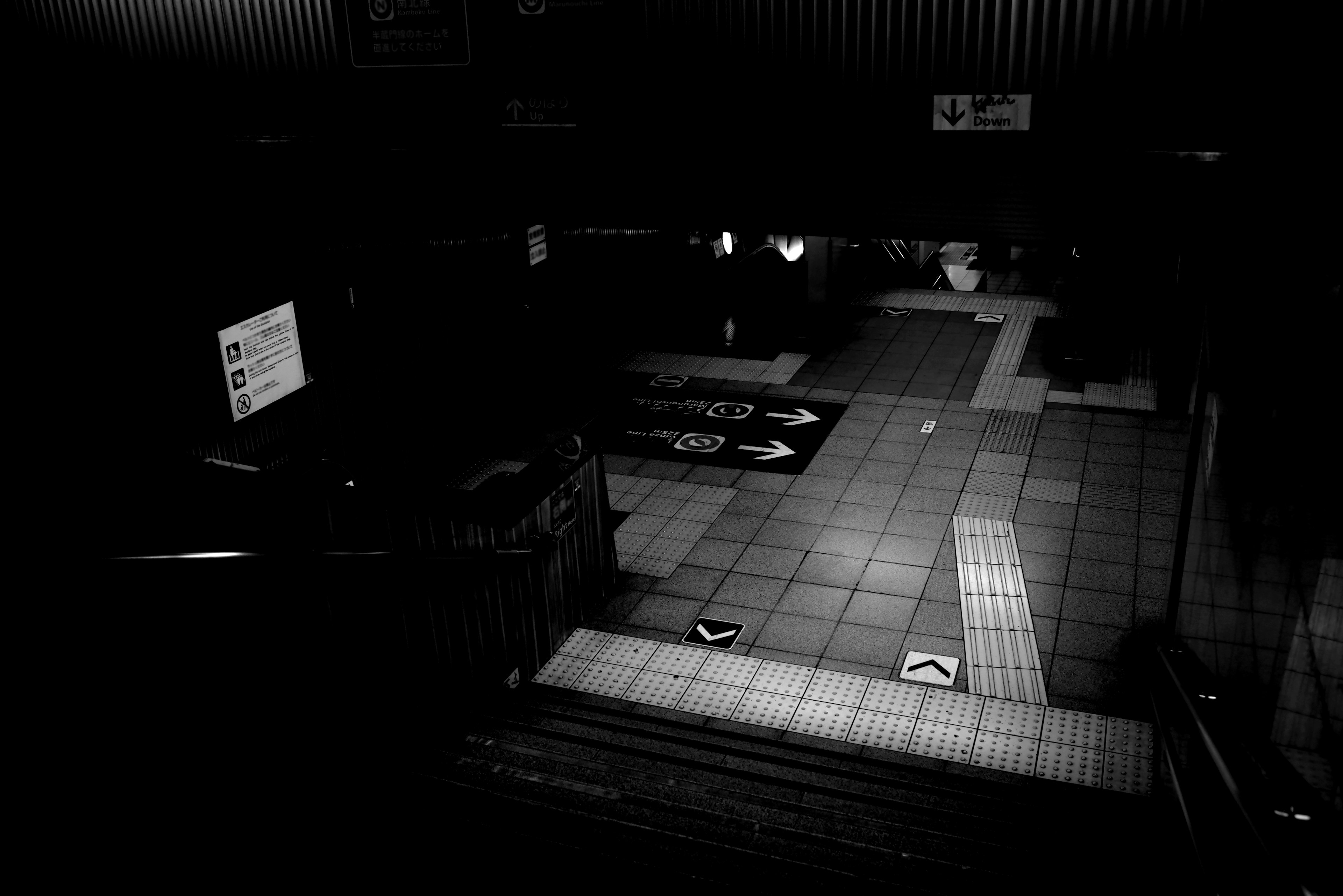 Dimly lit underground corridor with stairs and white arrows on the floor