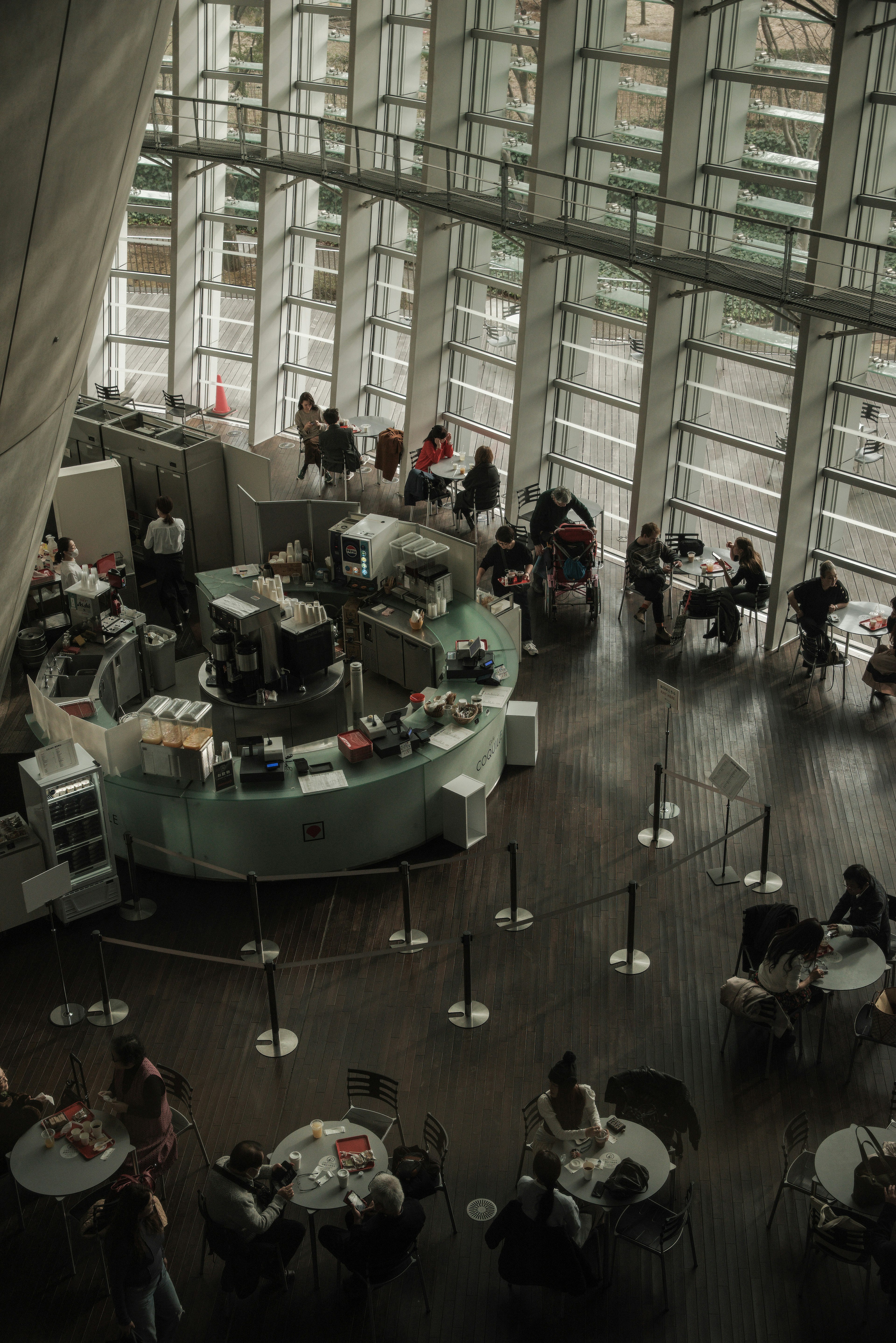 Interior de un café moderno con paredes de vidrio y personas sentadas en mesas