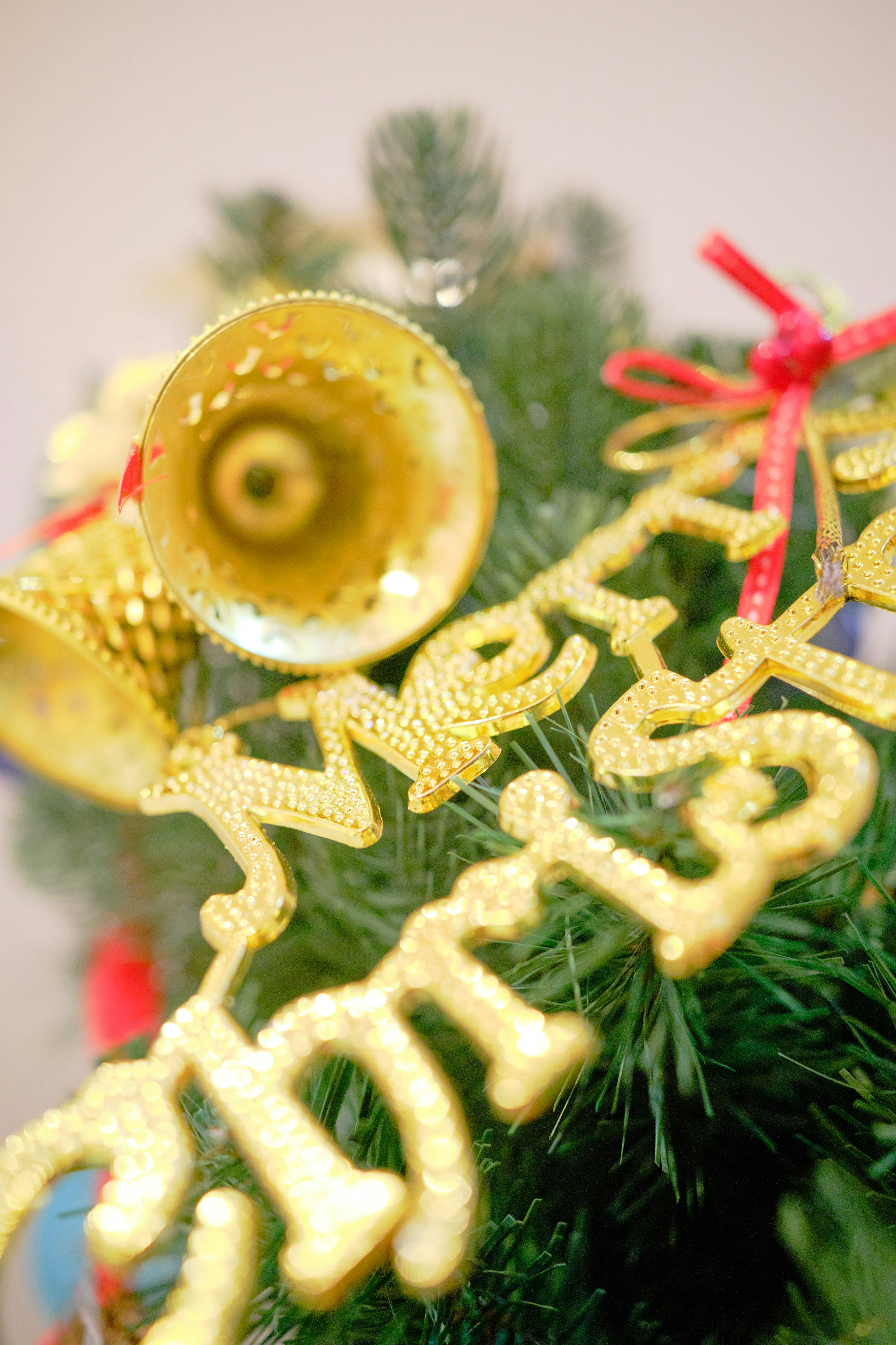 Acercamiento de decoraciones navideñas doradas y una campana en un árbol de Navidad