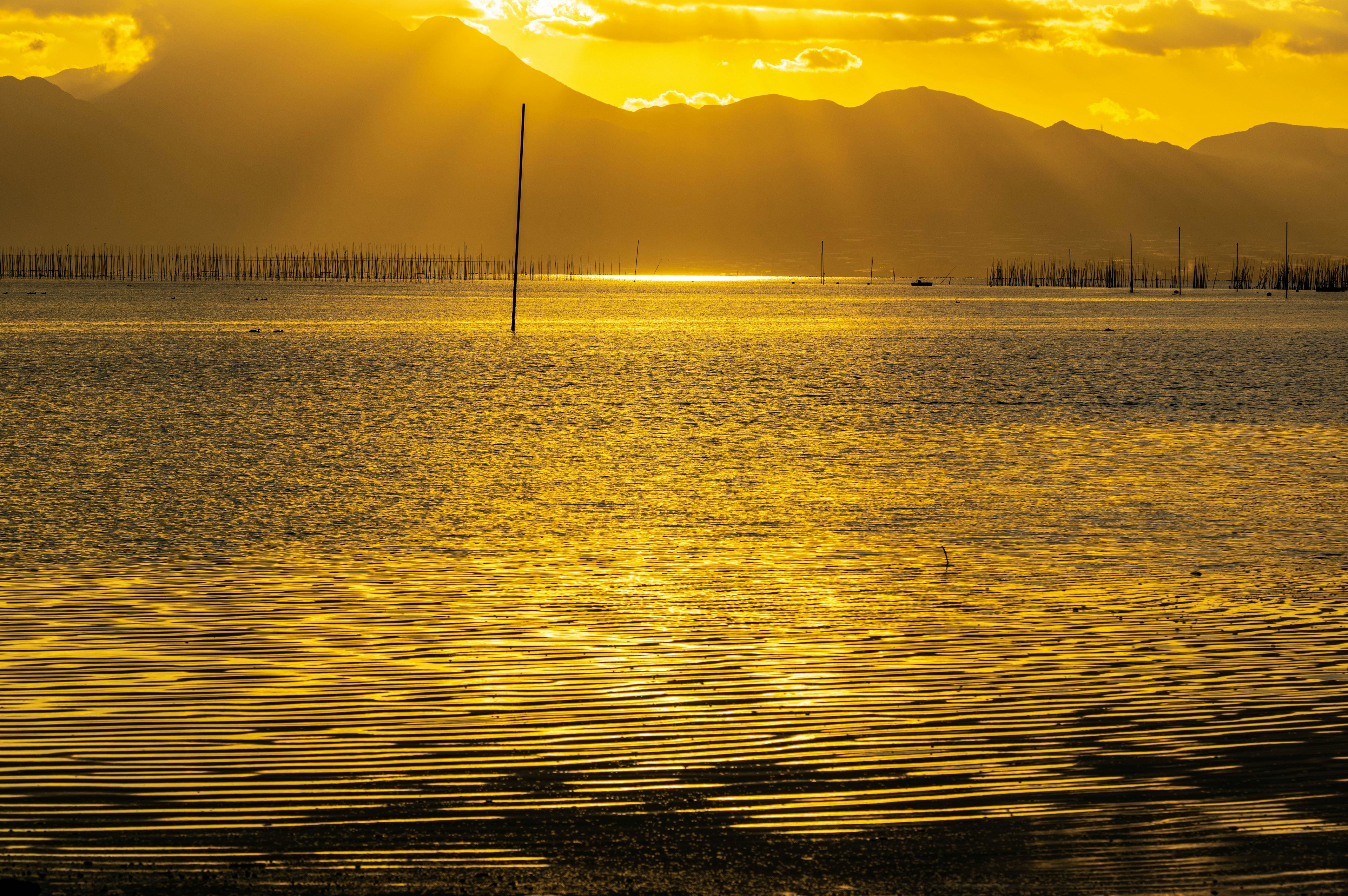 Goldener Sonnenuntergang, der sich auf einer ruhigen Wasseroberfläche spiegelt