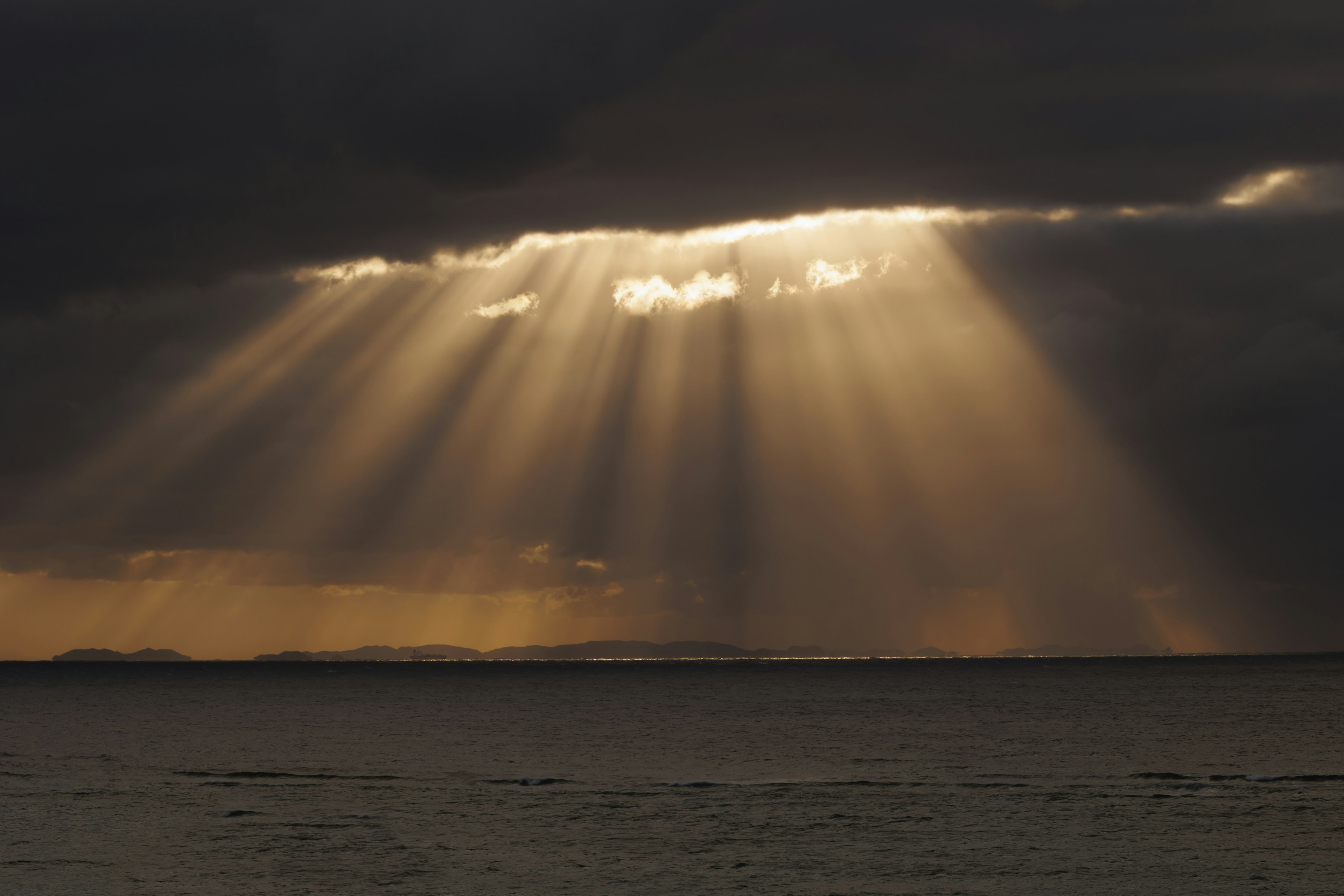 Paesaggio misterioso con raggi di luce che filtrano attraverso nuvole scure sopra il mare