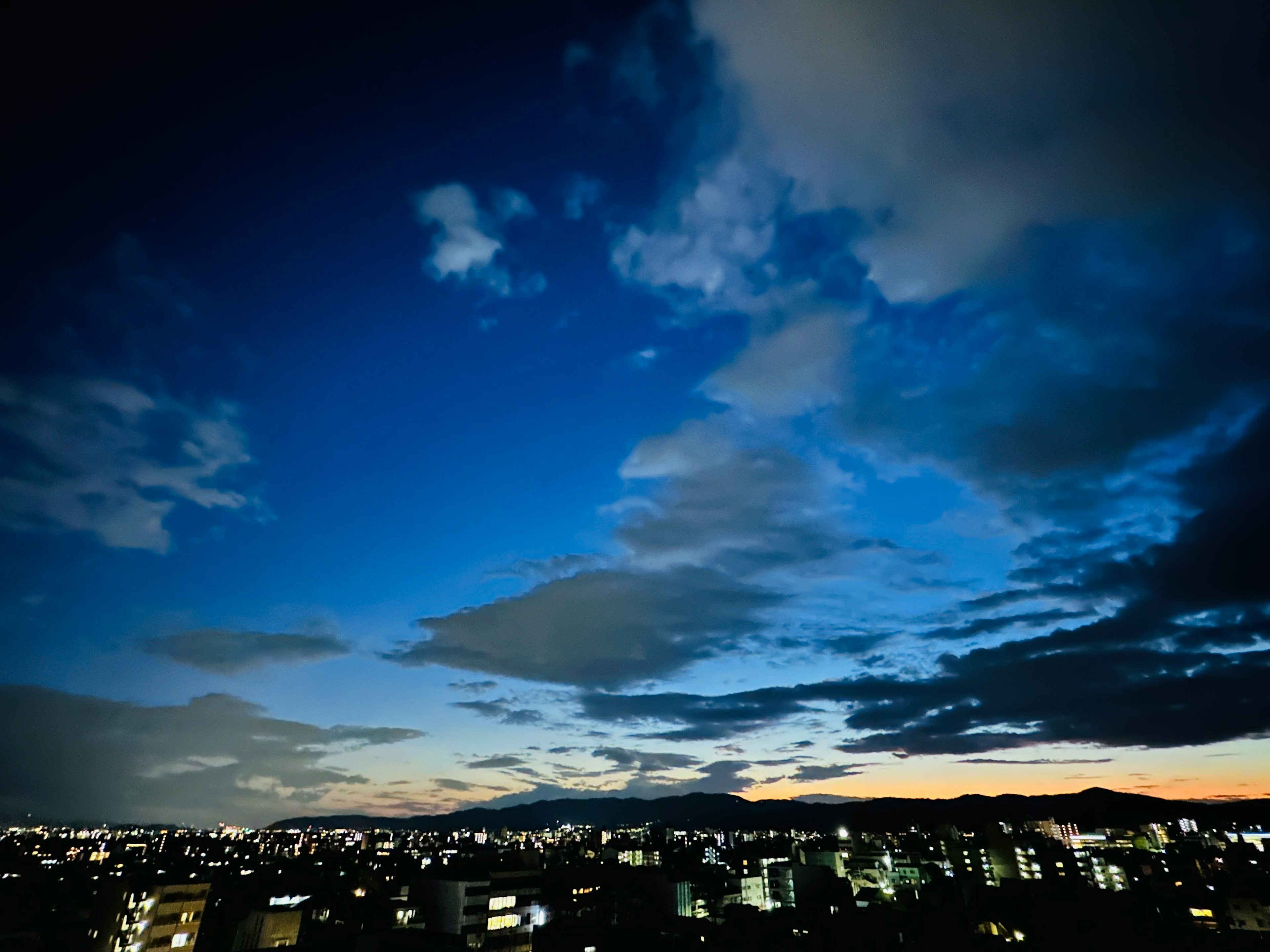 Skyline urbana al crepuscolo con luci di città brillanti e cielo blu