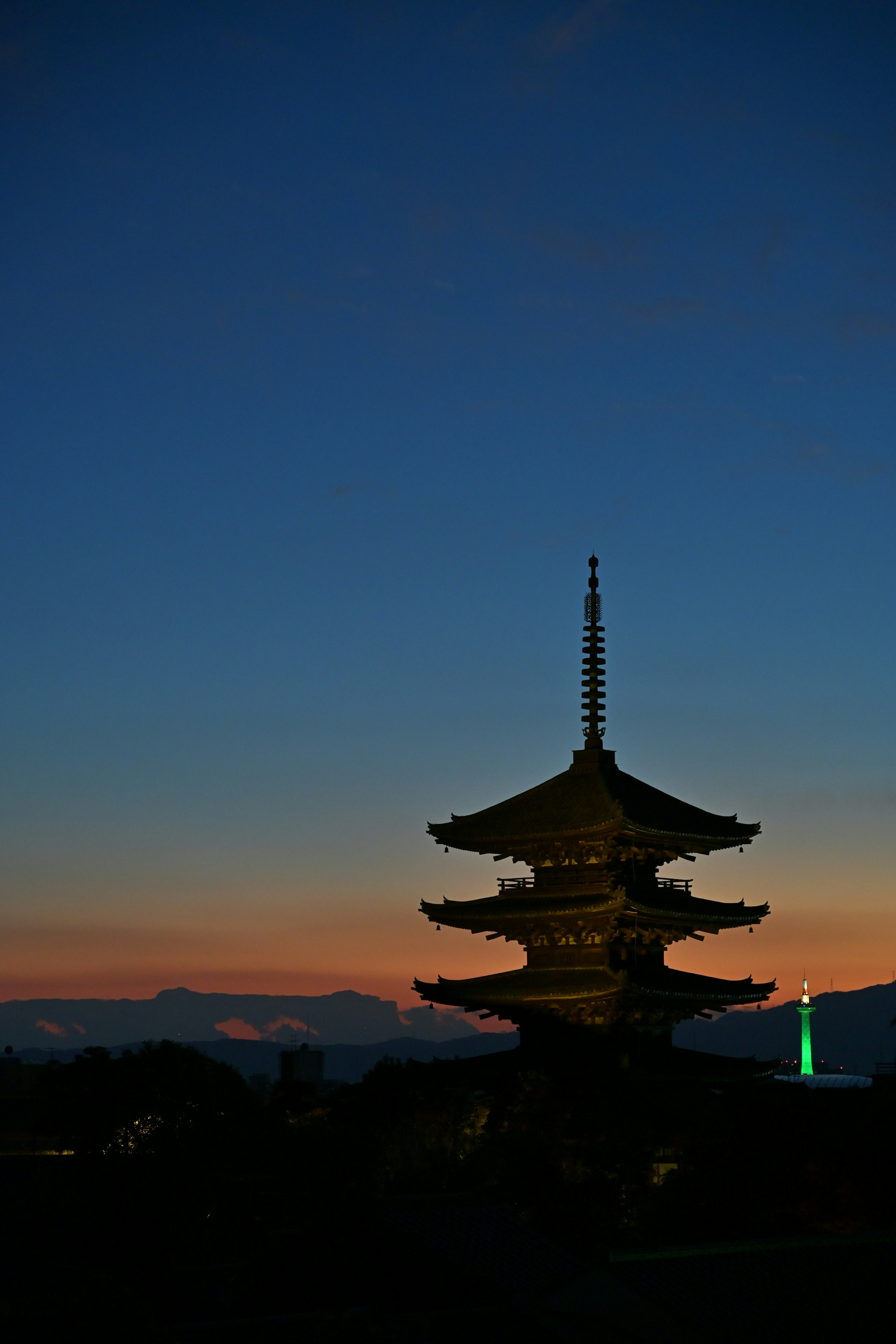 Silhouette of a pagoda at dusk with distant mountains