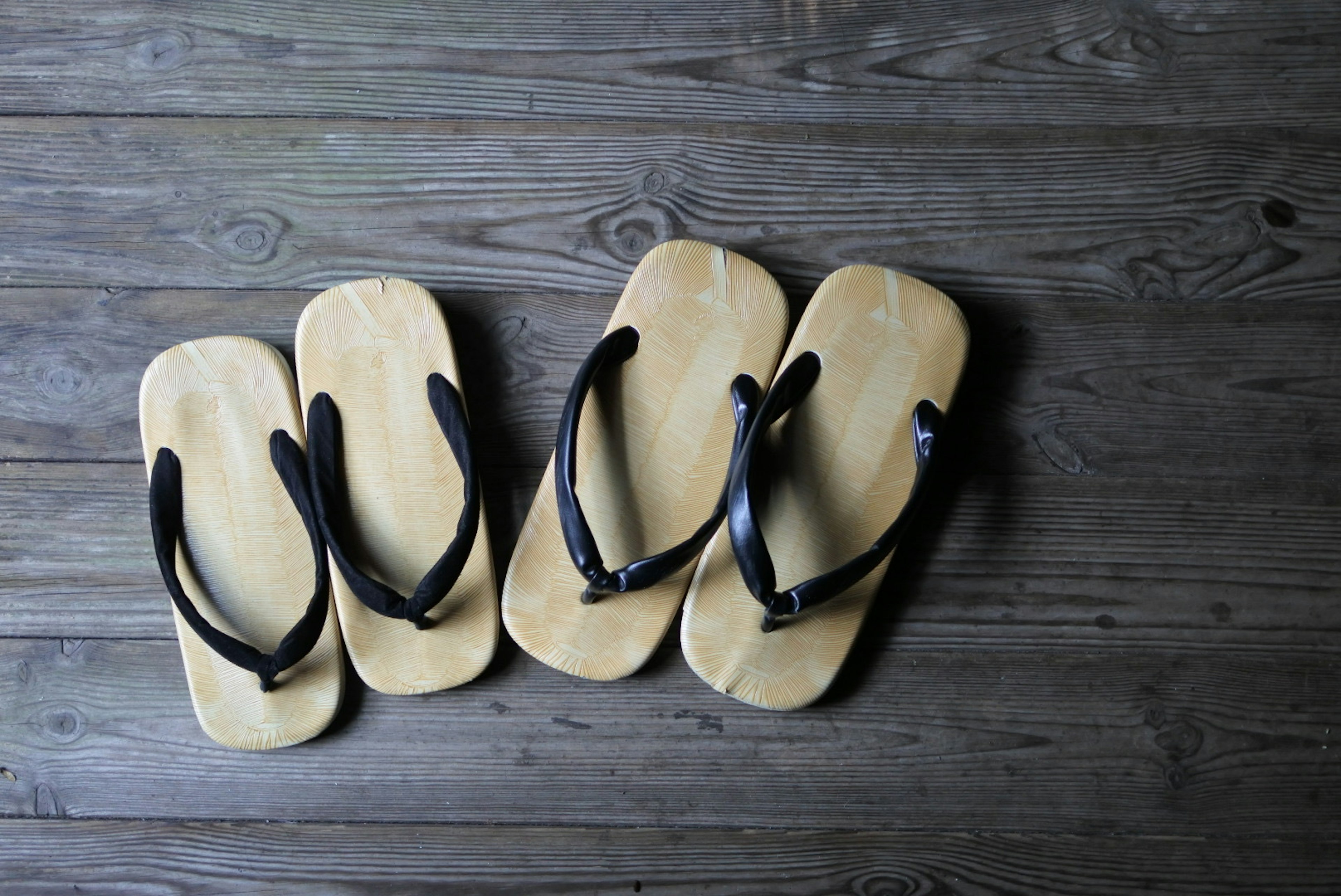 Two pairs of wooden sandals arranged on a wooden surface