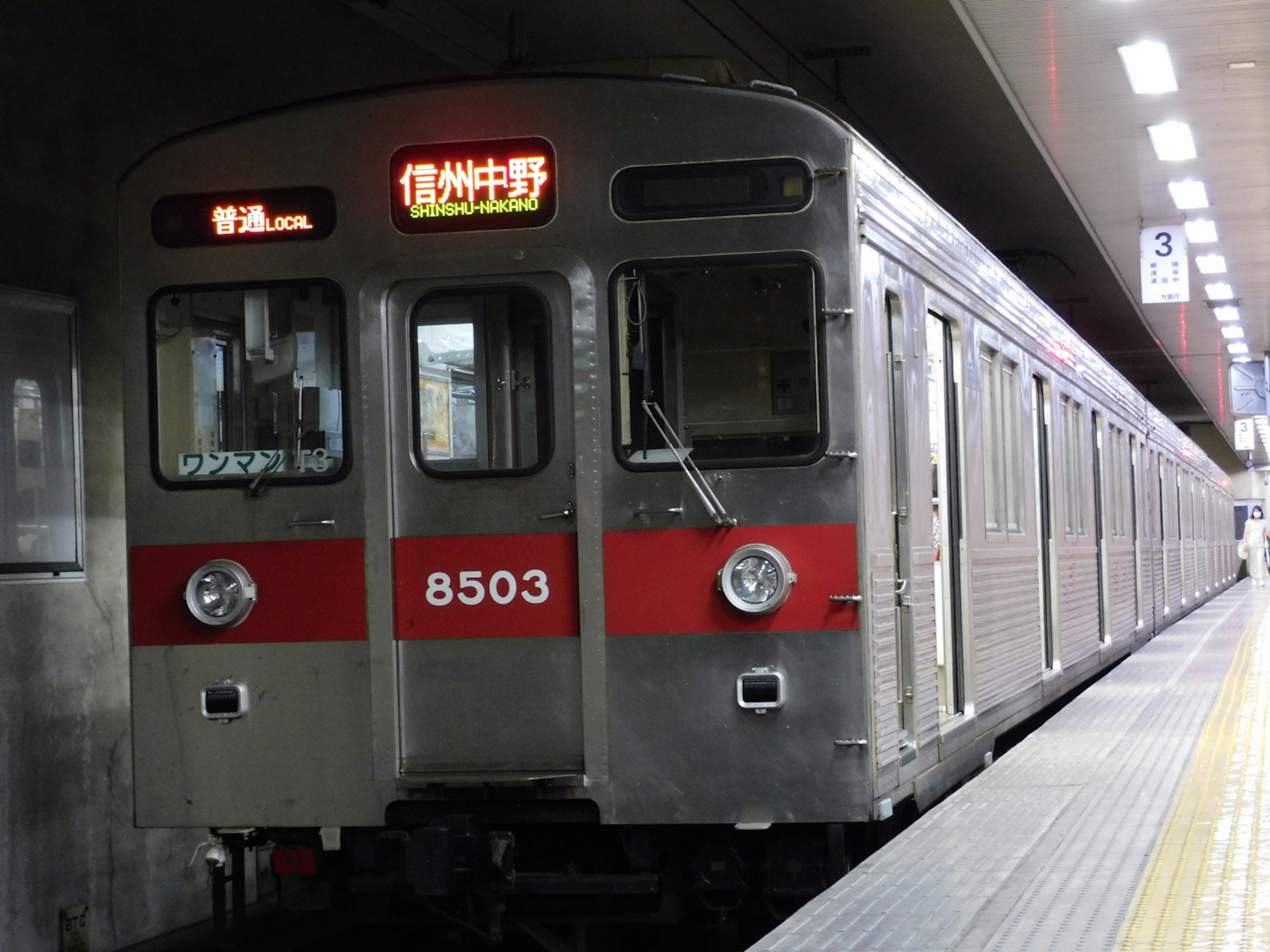 Train argent numéro 8503 avec des rayures rouges à la gare