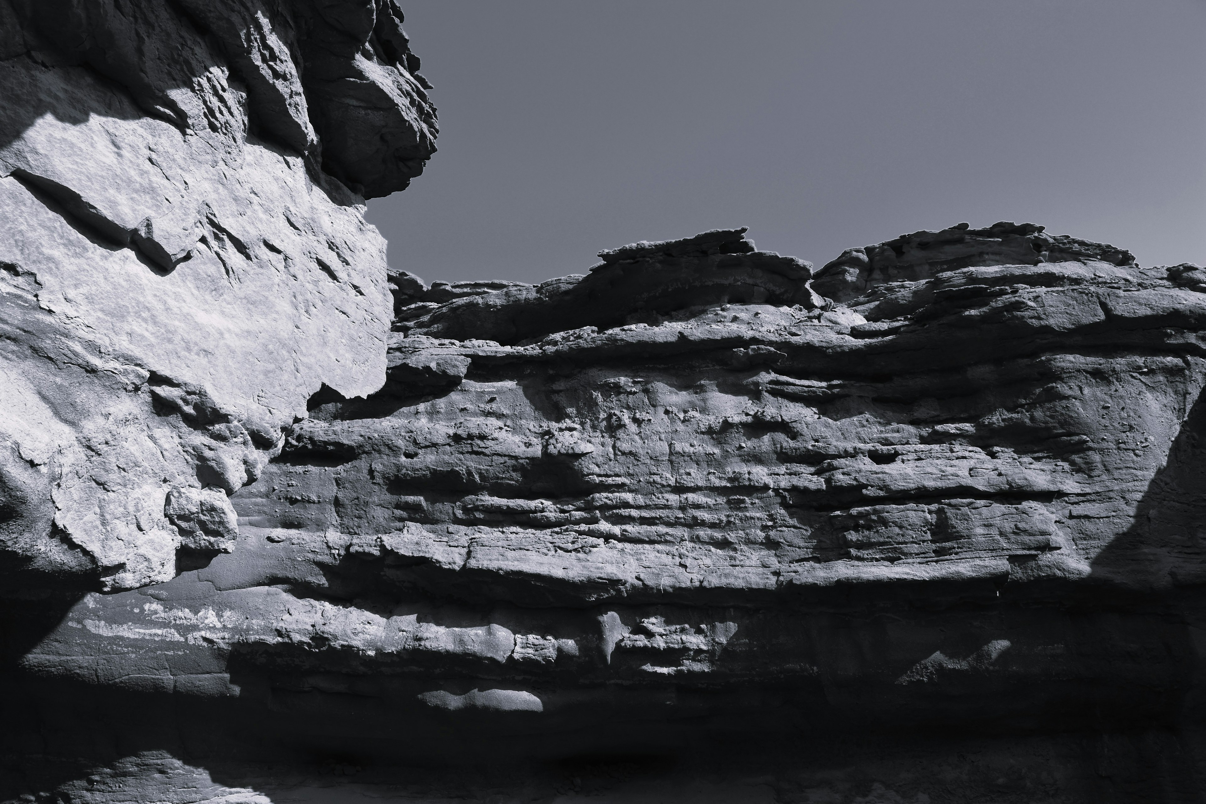 Black and white image of towering rock layers against the sky