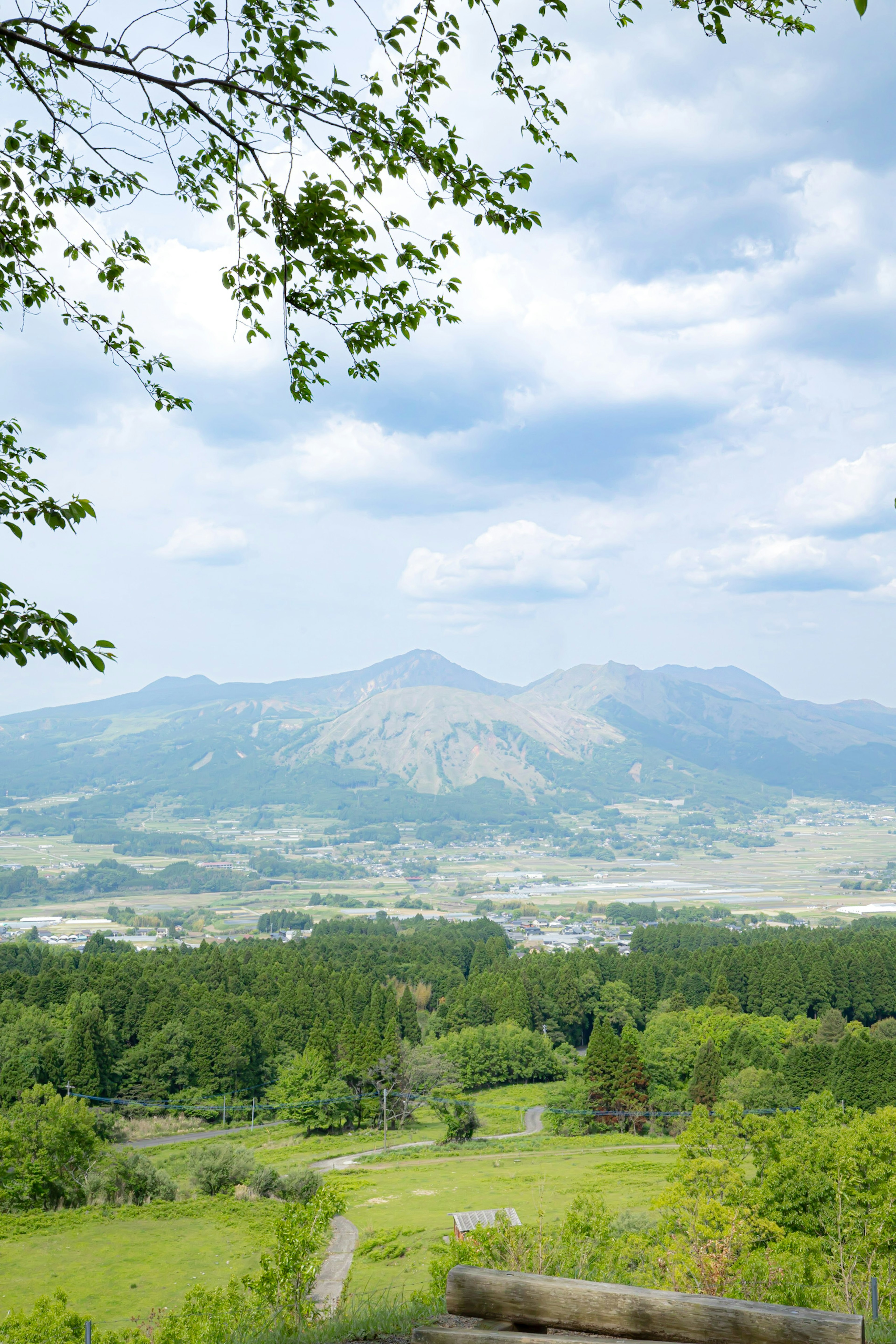 Lush green hills and mountains under a blue sky with white clouds