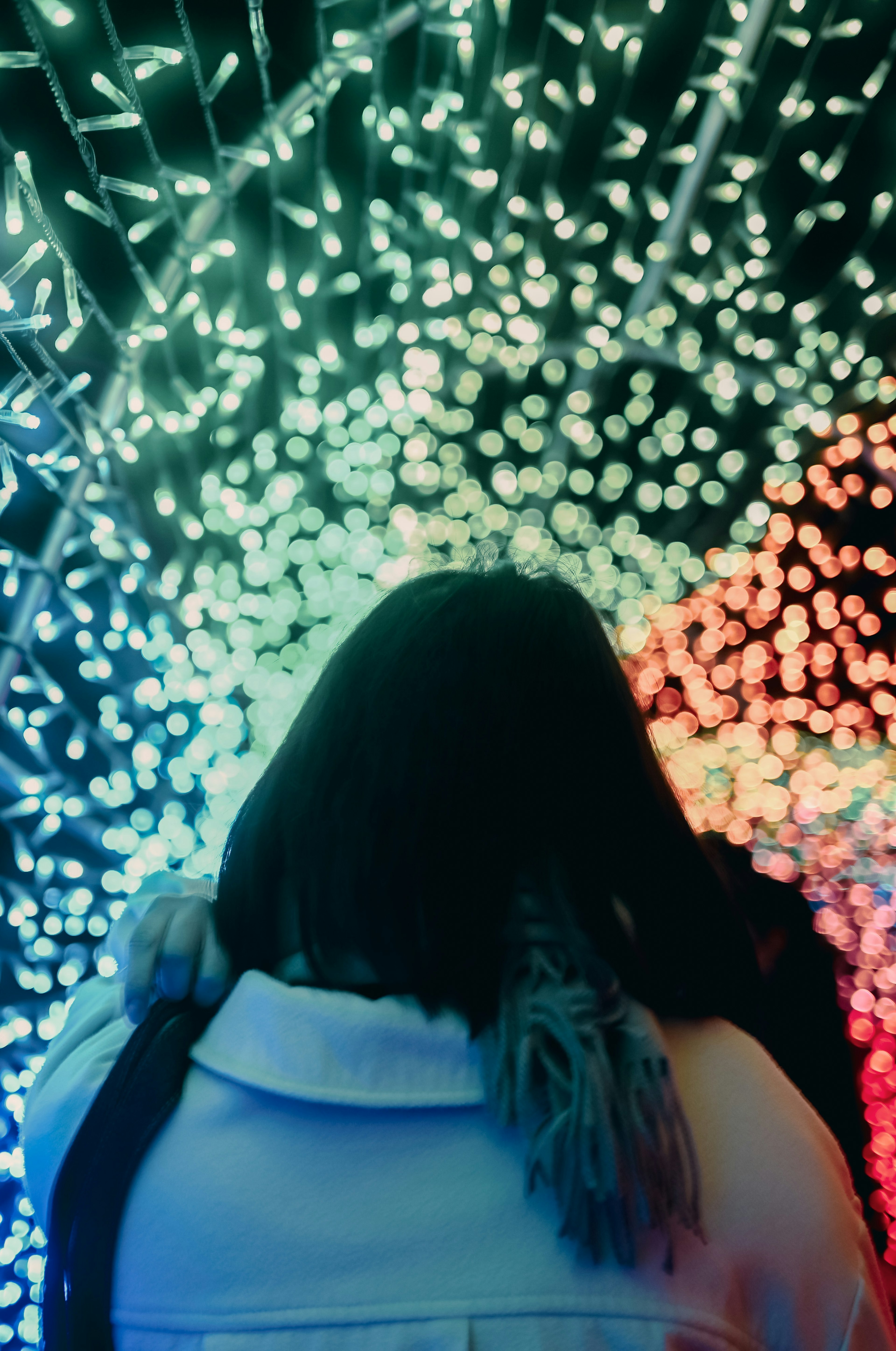 Una mujer mirando hacia arriba un túnel de luces coloridas desde atrás