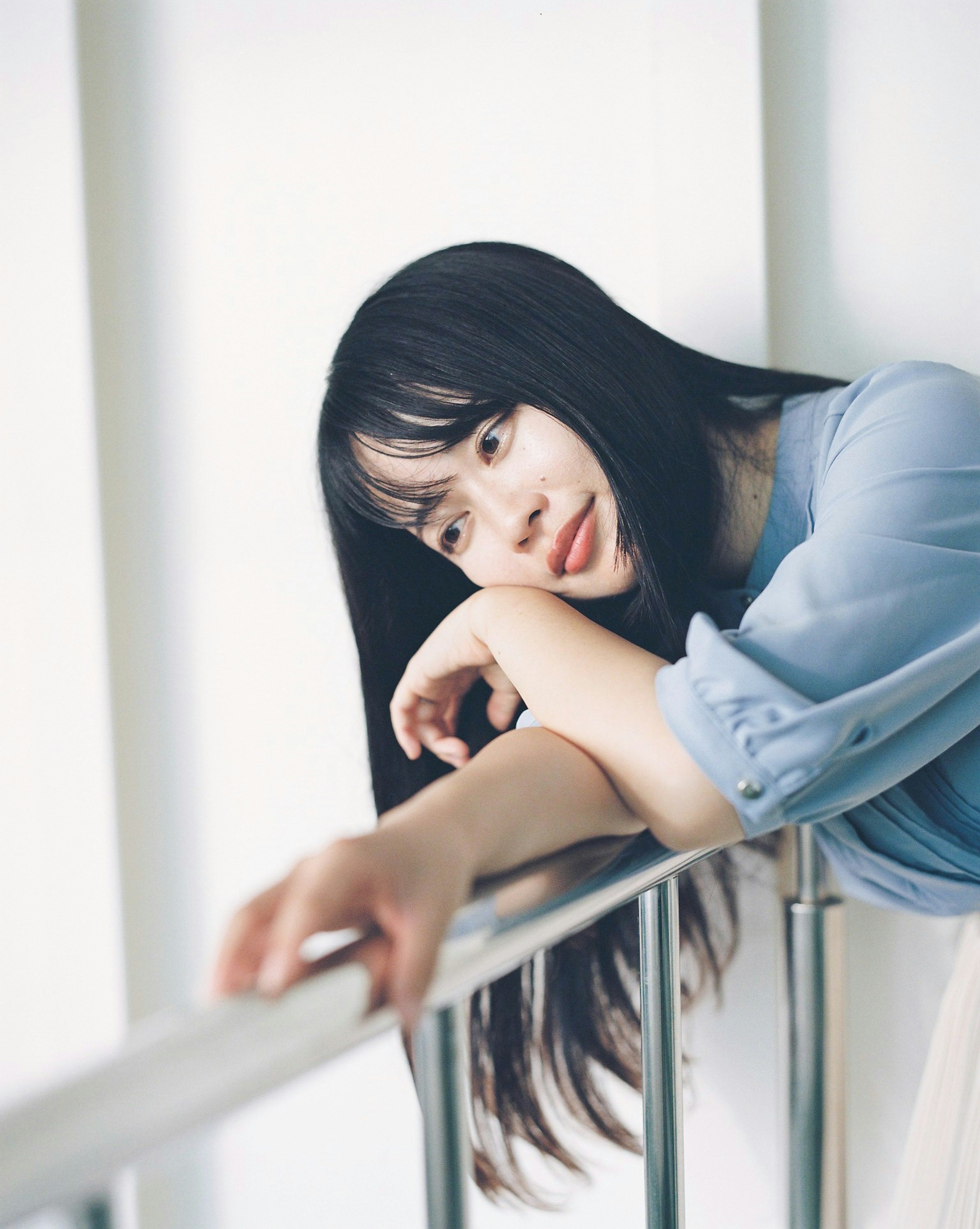 Portrait of a woman resting her arms on a railing by a window