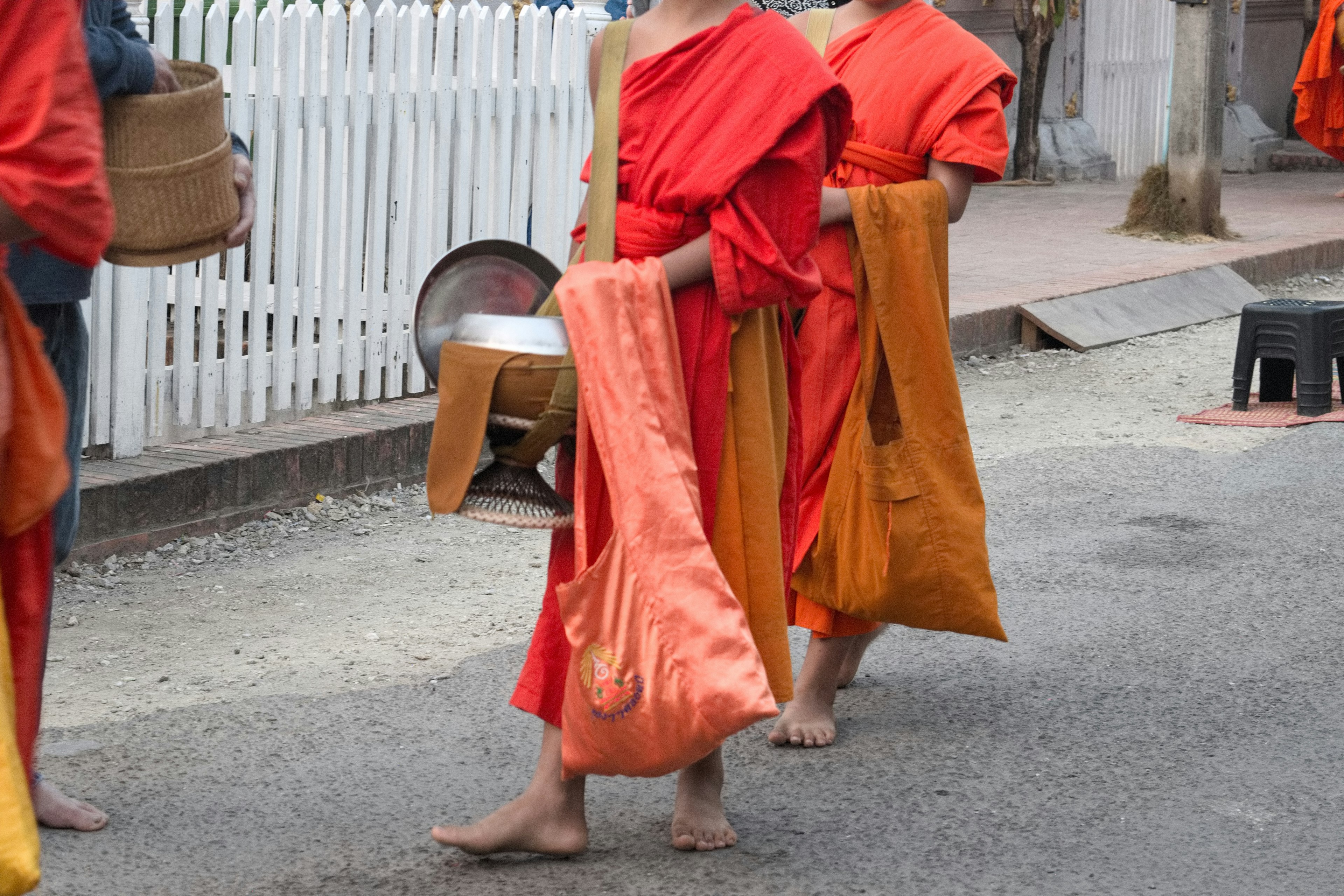 Các sư thầy trong áo cà sa màu cam đi bộ trên đường