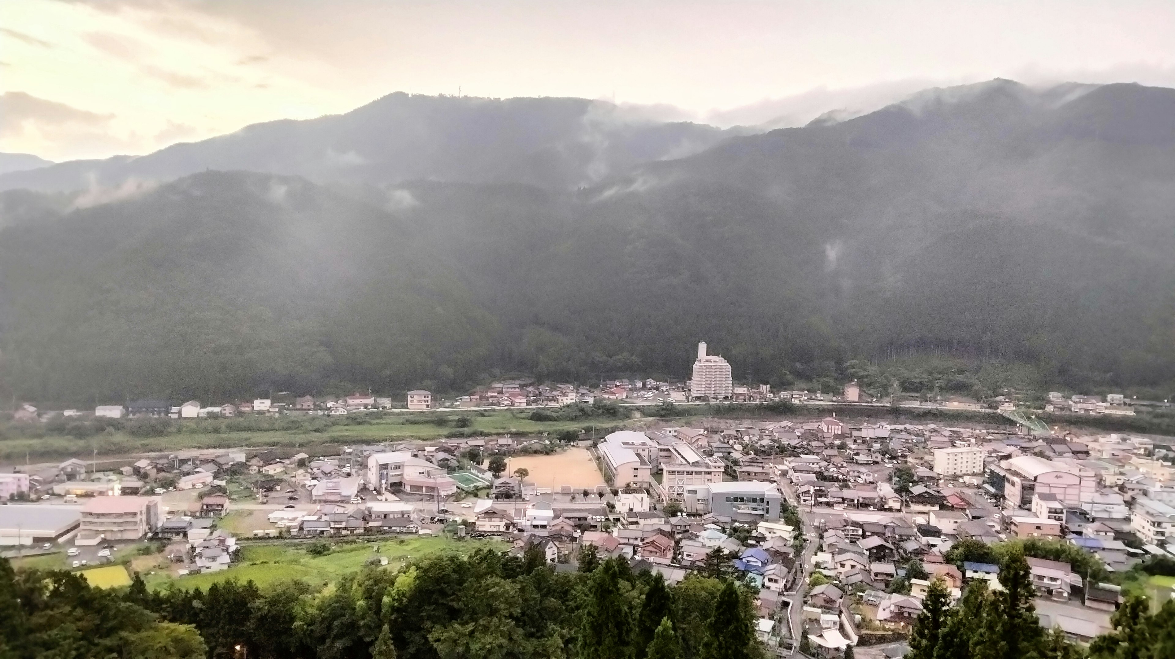 Vista panorámica de un pueblo rodeado de hermosas montañas y niebla