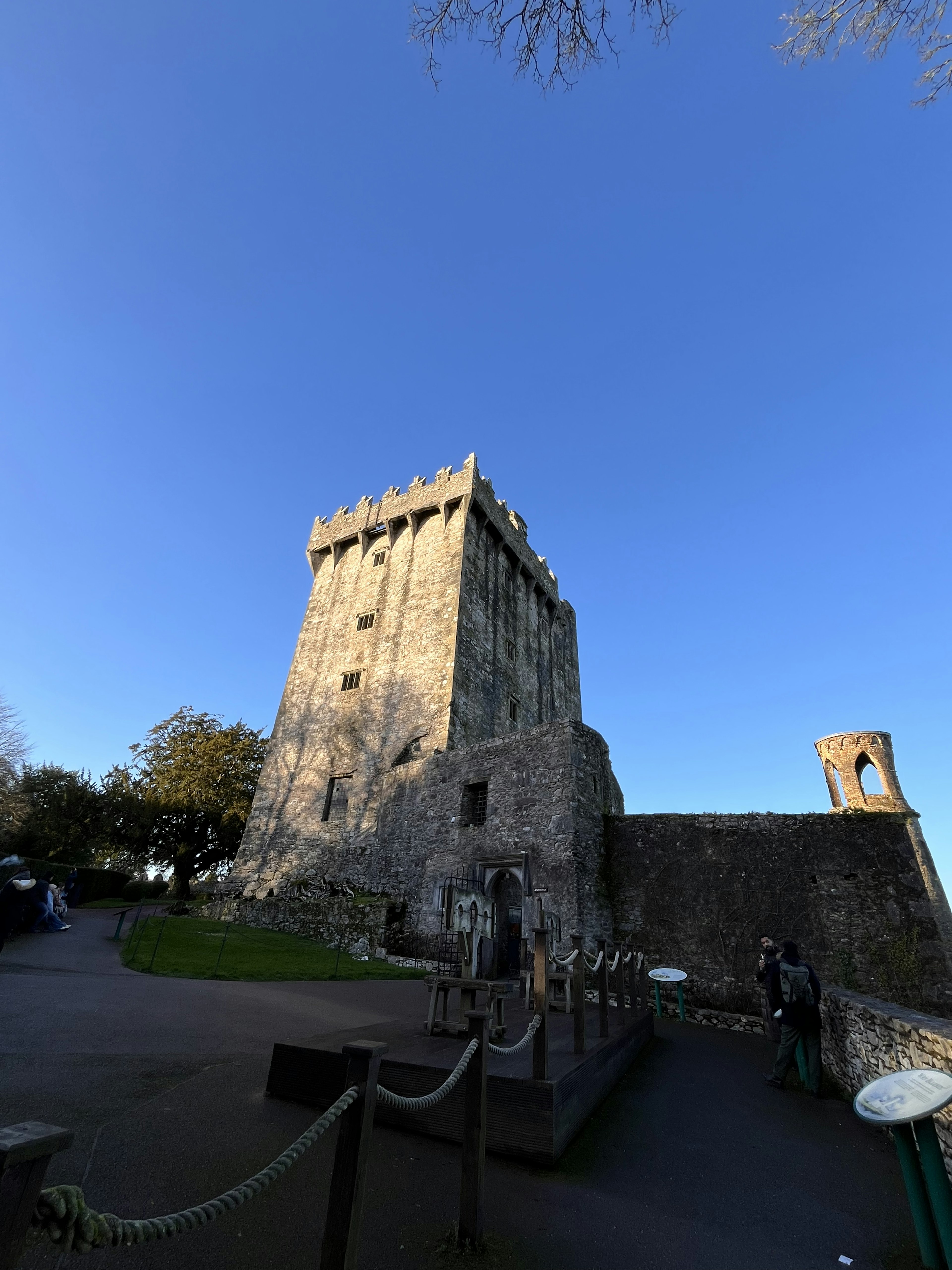 Una torre di pietra antica sotto un cielo blu chiaro con vegetazione circostante