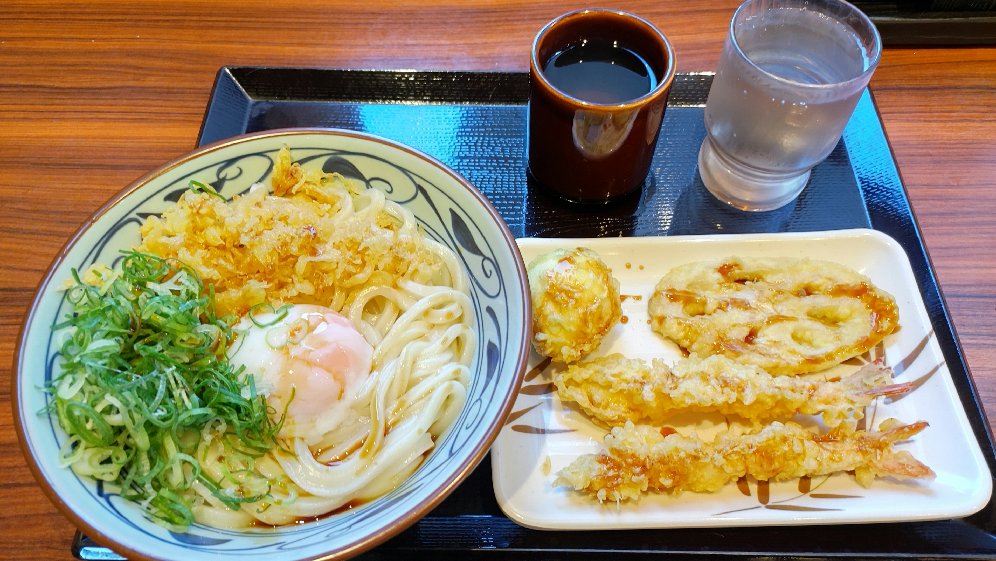 うどんと天ぷらの皿が並ぶ日本の食事