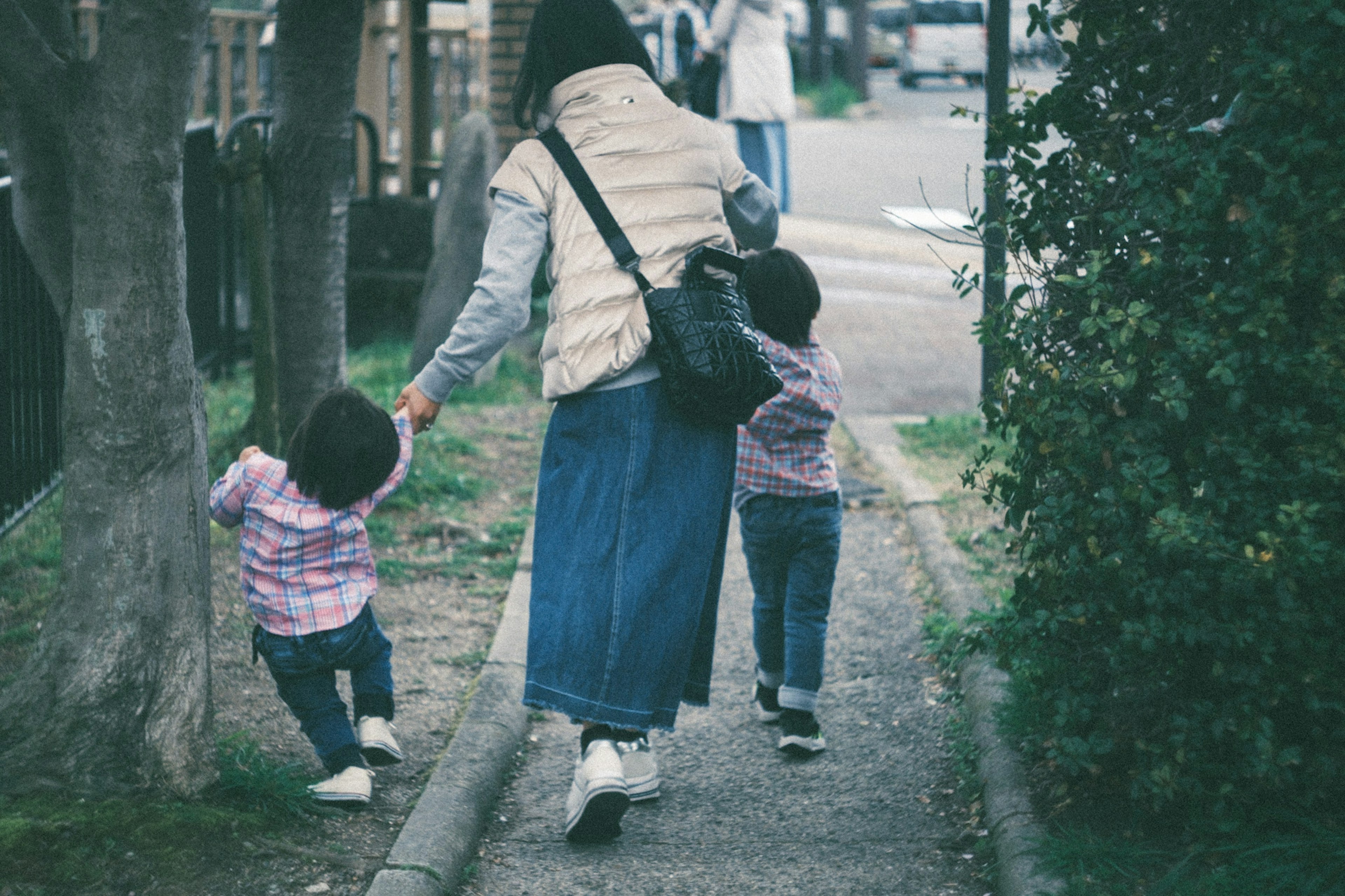 Seorang ibu berjalan dengan dua anak di jalan