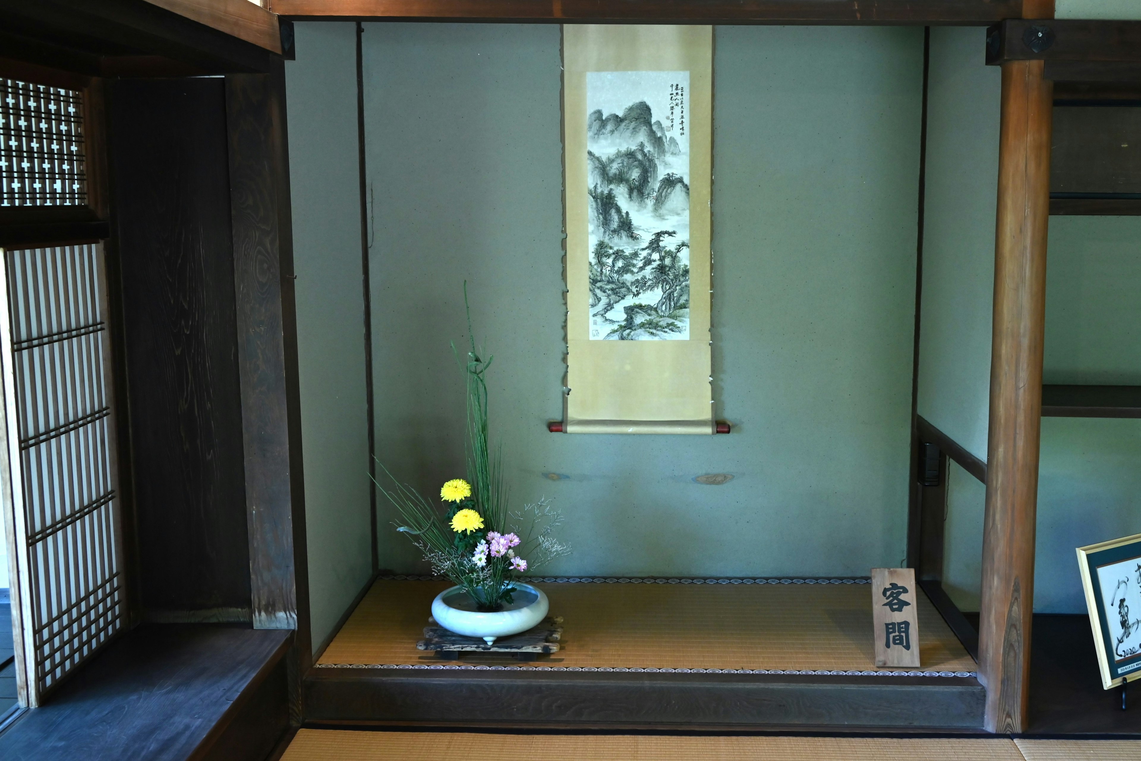 A traditional Japanese room featuring a flower arrangement and a hanging scroll