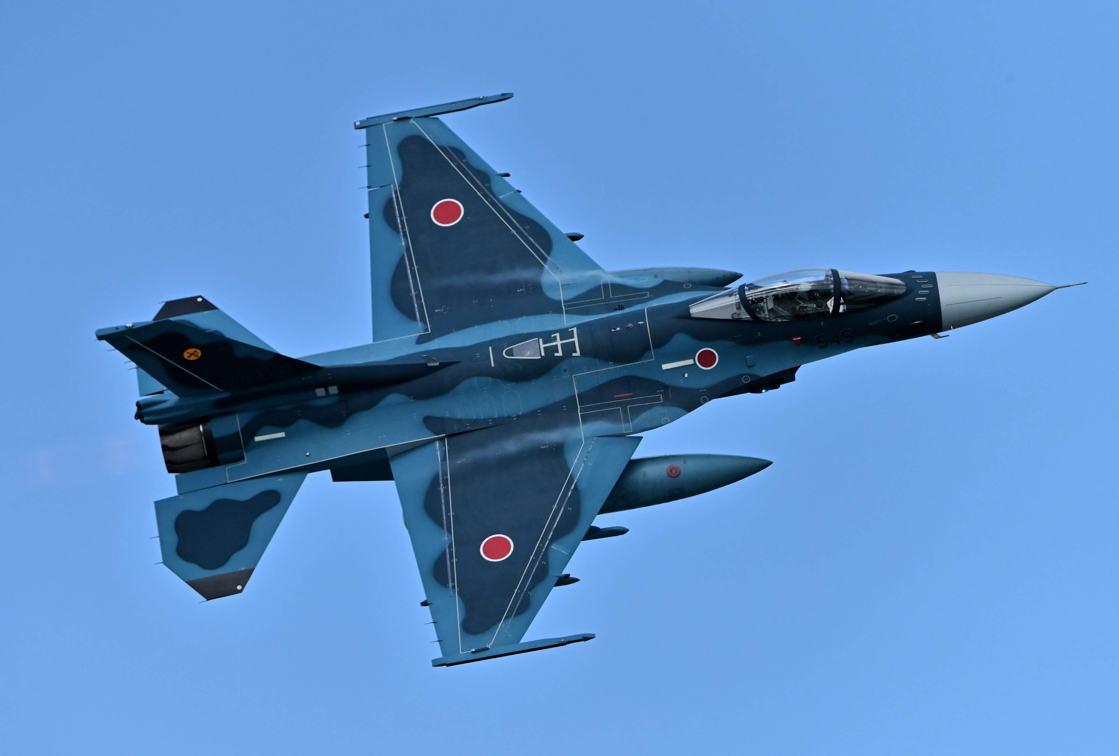 Blue camouflage fighter jet flying in the sky