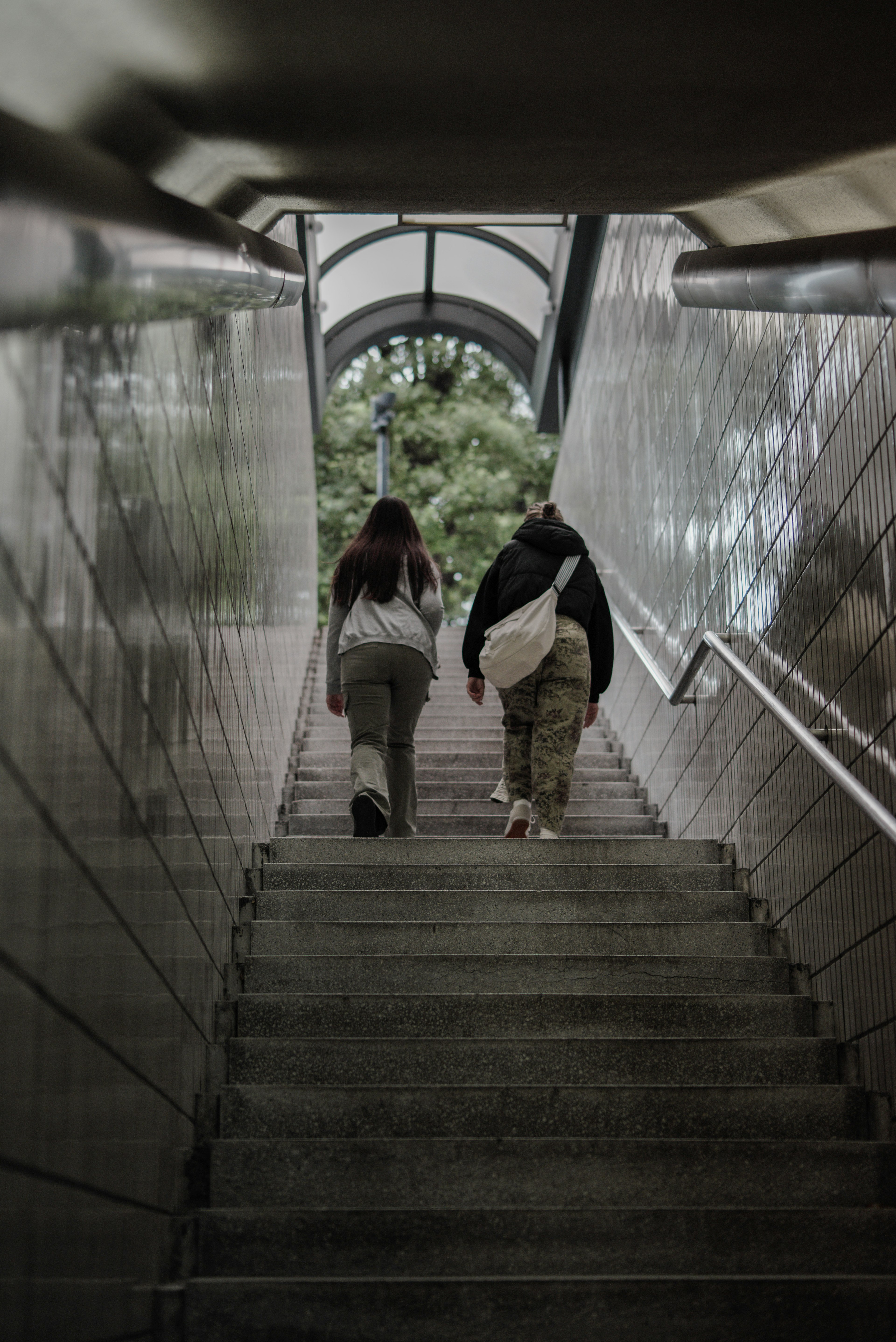 Two people ascending stairs under a lit arcade