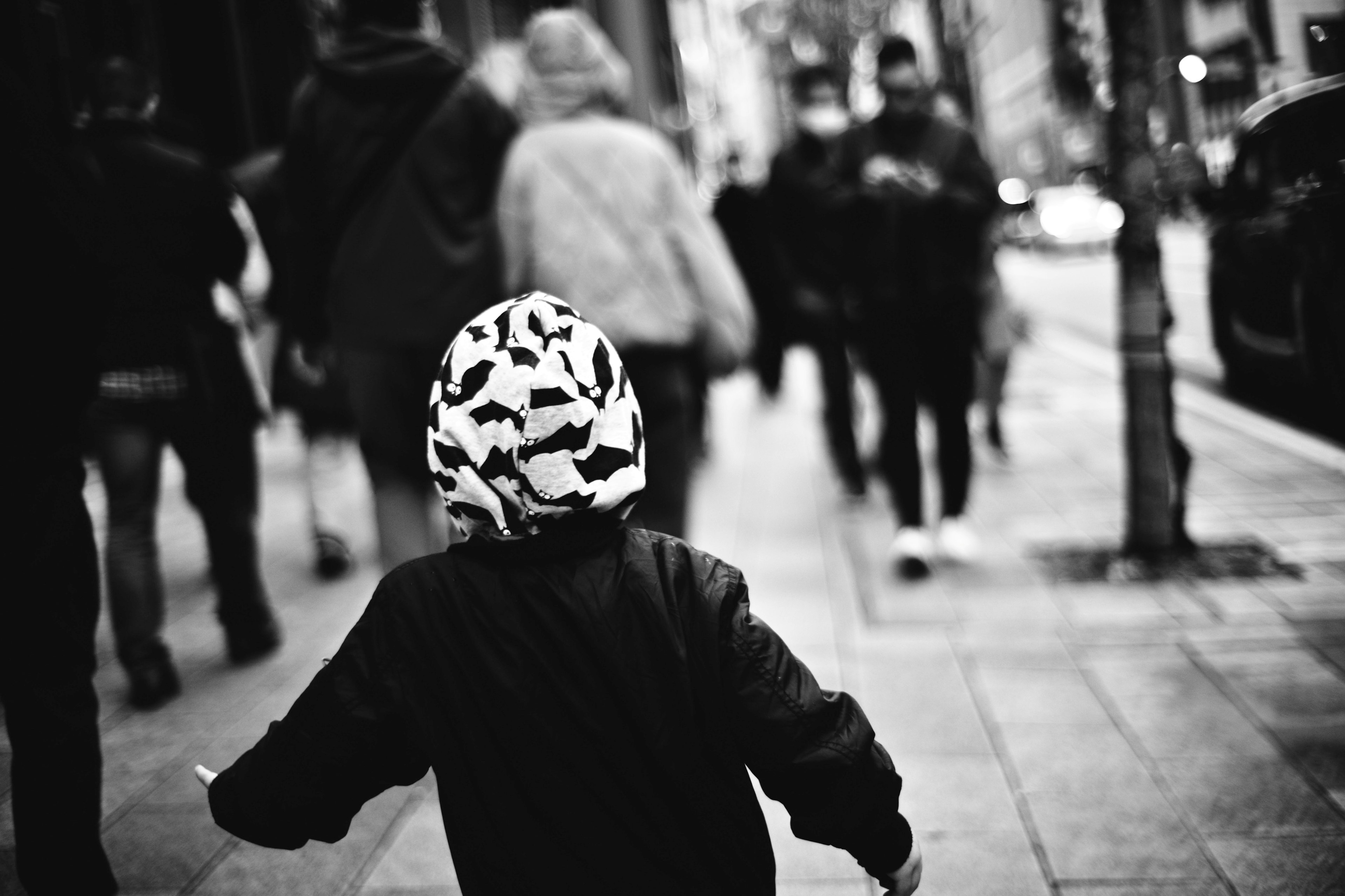 Niño corriendo en una calle en blanco y negro con personas caminando alrededor