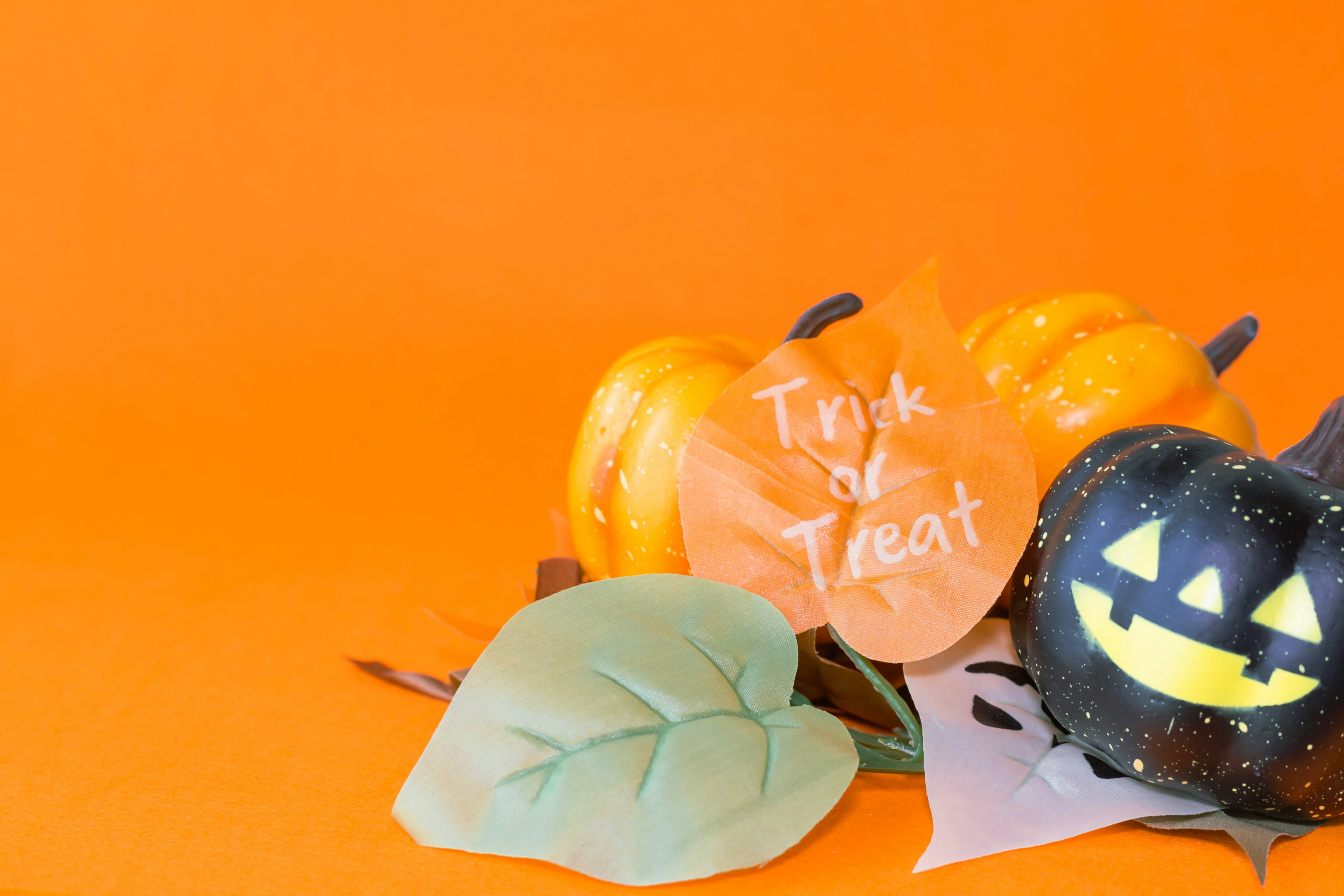 Calabazas de Halloween y hojas dispuestas sobre un fondo naranja