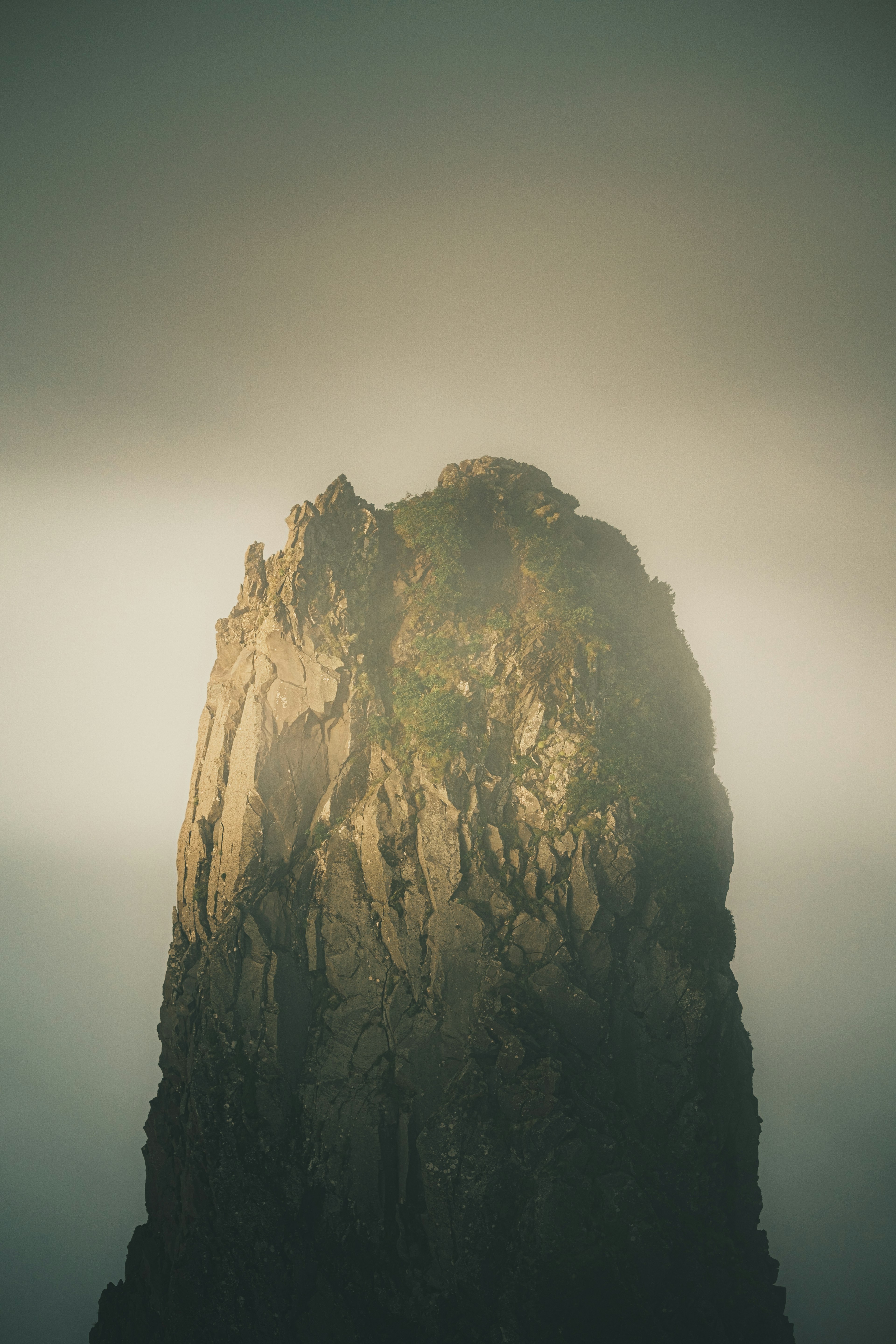 Image of a mountain peak illuminated by light surrounded by mist