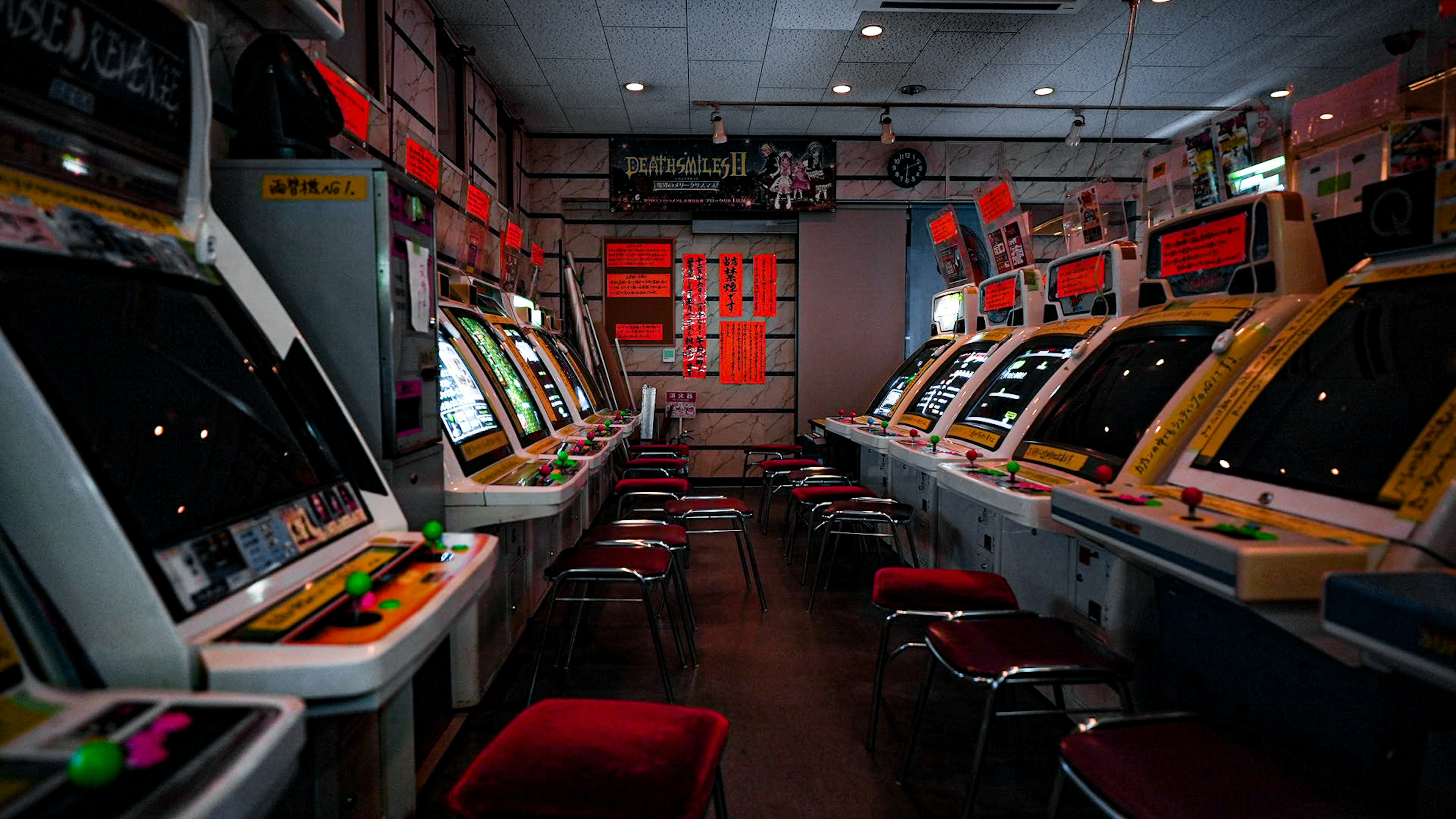 Innenansicht einer Spielhalle mit Vintage-Spielautomaten und roten Stühlen