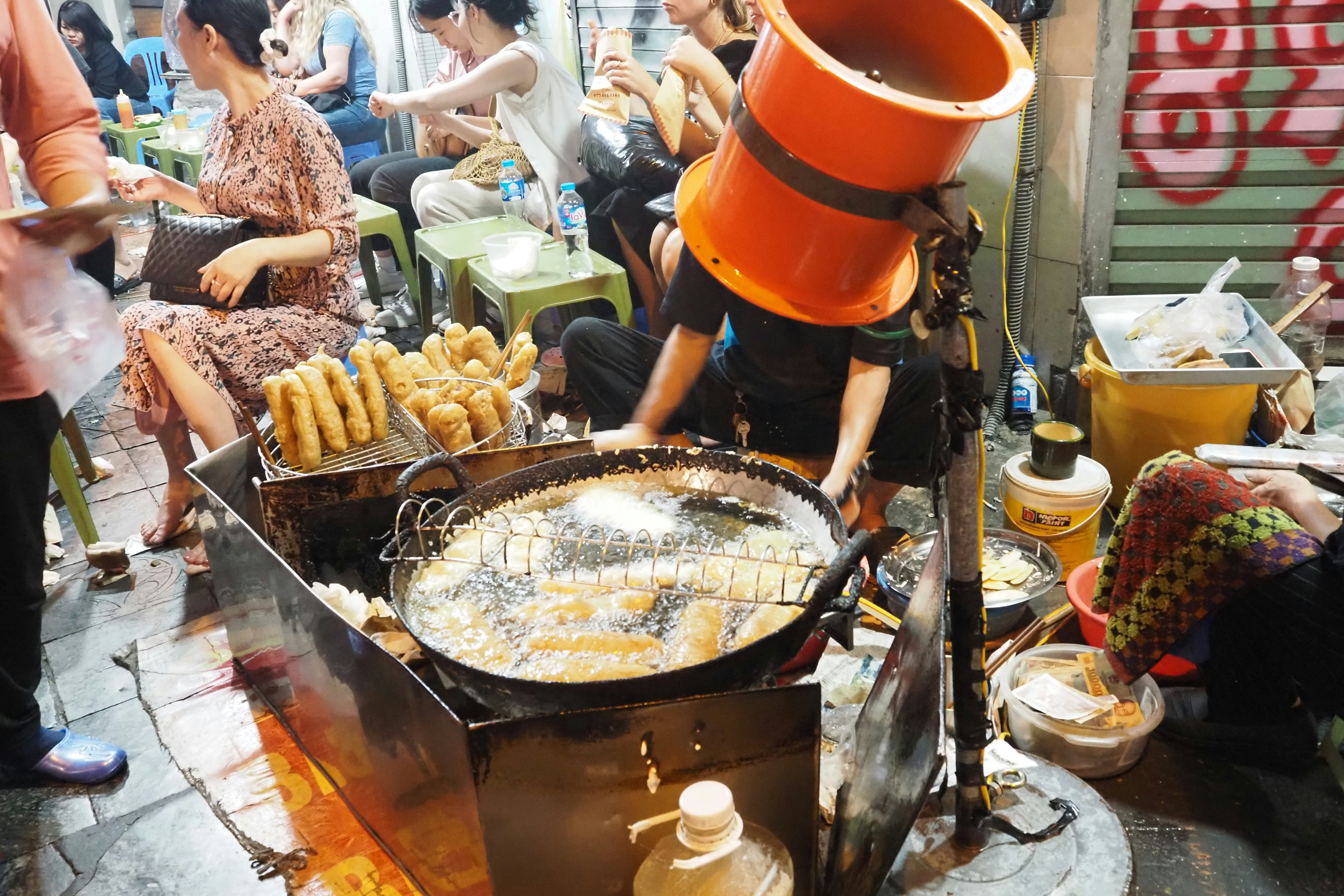 Chiosco di street food che frigge snack in una scena di mercato notturno affollato