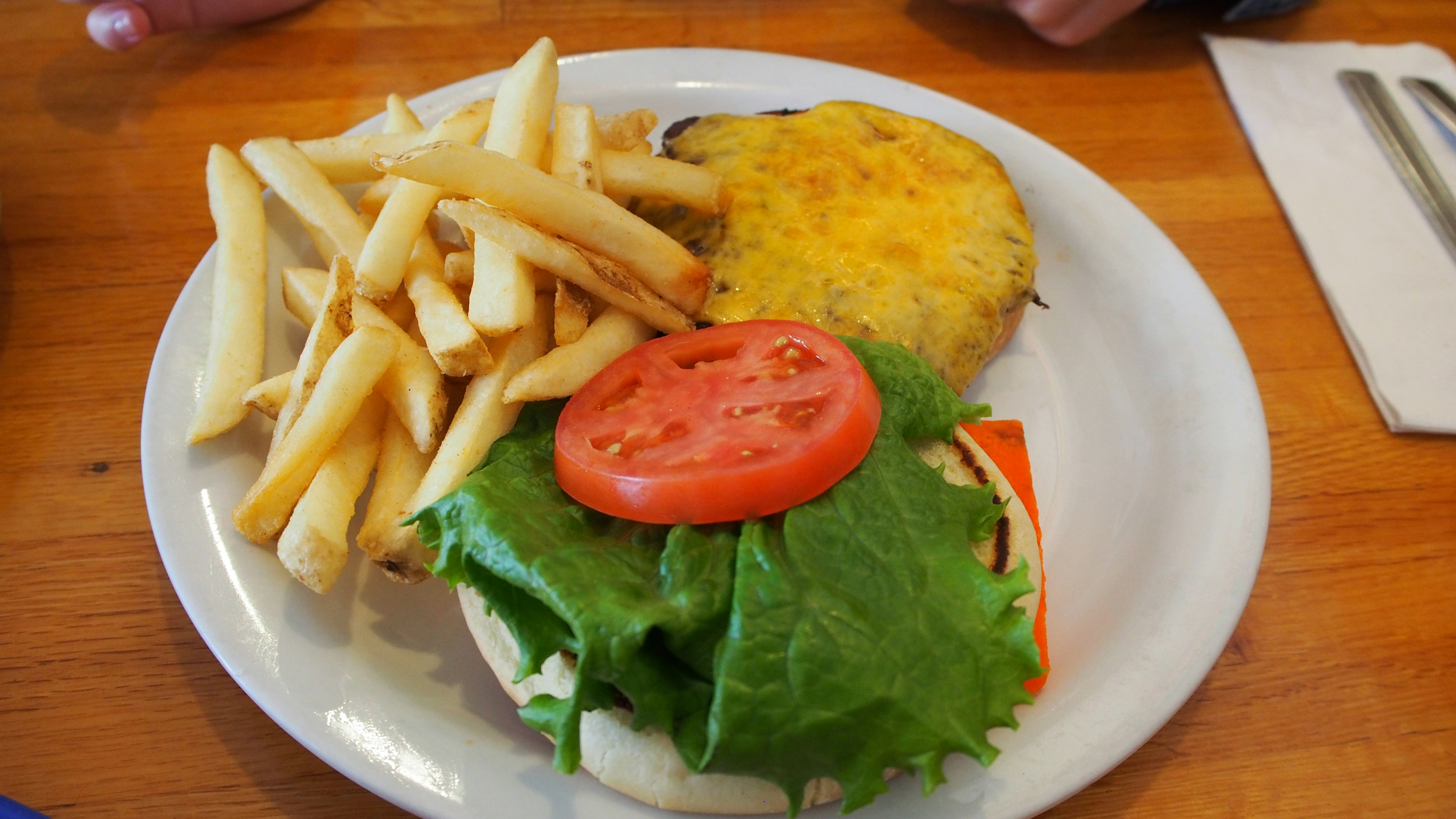 Une assiette avec un sandwich contenant de la laitue et de la tomate accompagné de frites