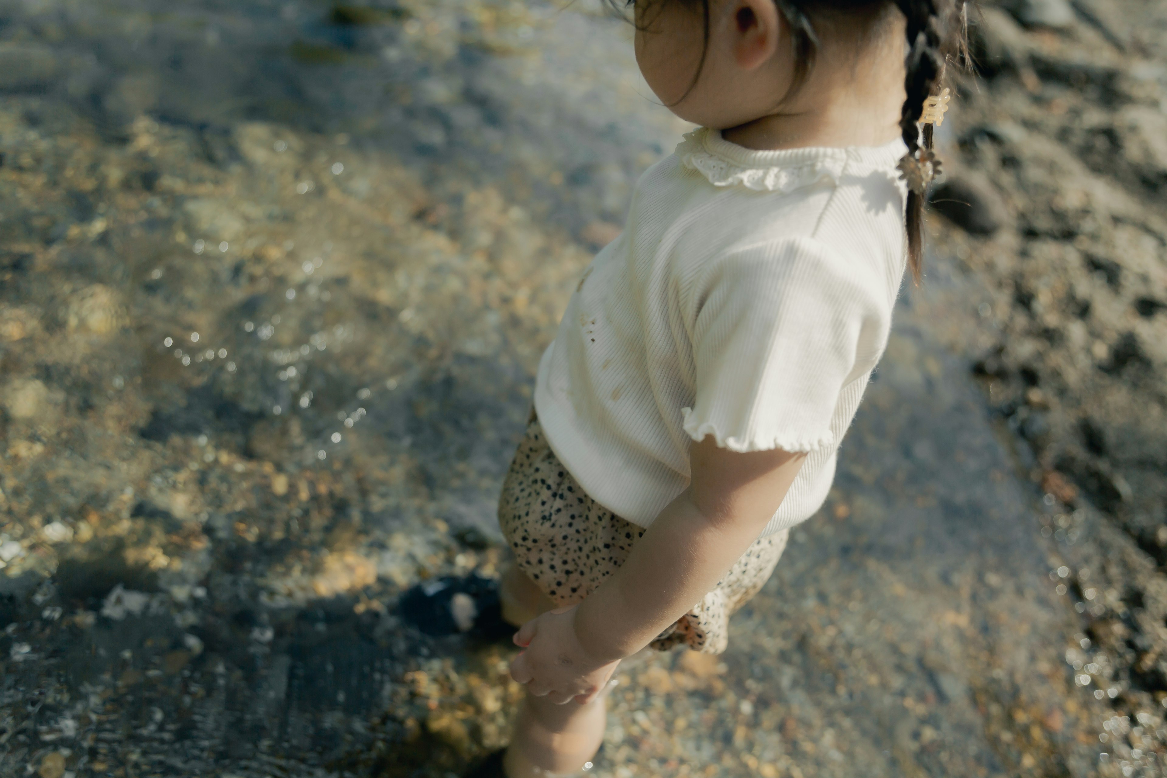 海辺で水に足を浸している子供の後ろ姿