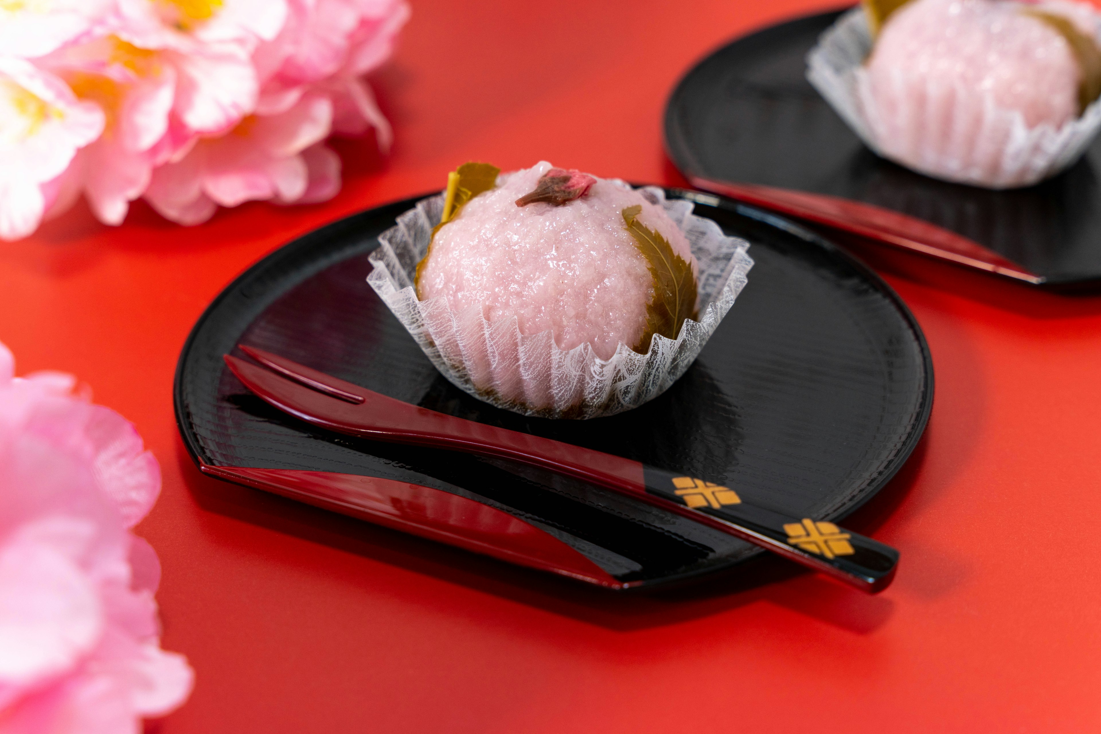 Wunderschönes Dessert mit Sakura-Mochi auf einem schwarzen Teller