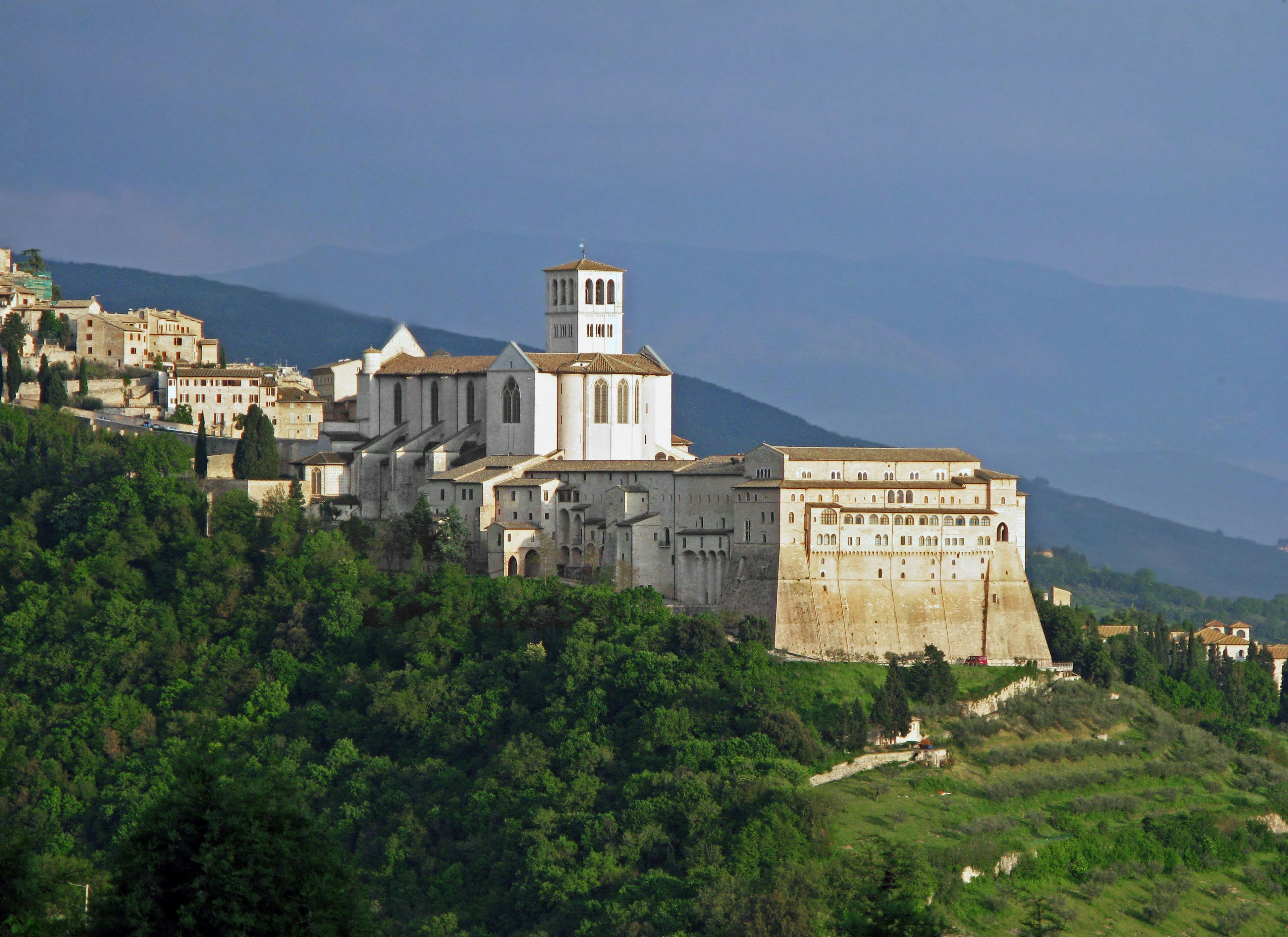 Basilica of Saint Francis in Assisi surrounded by lush greenery