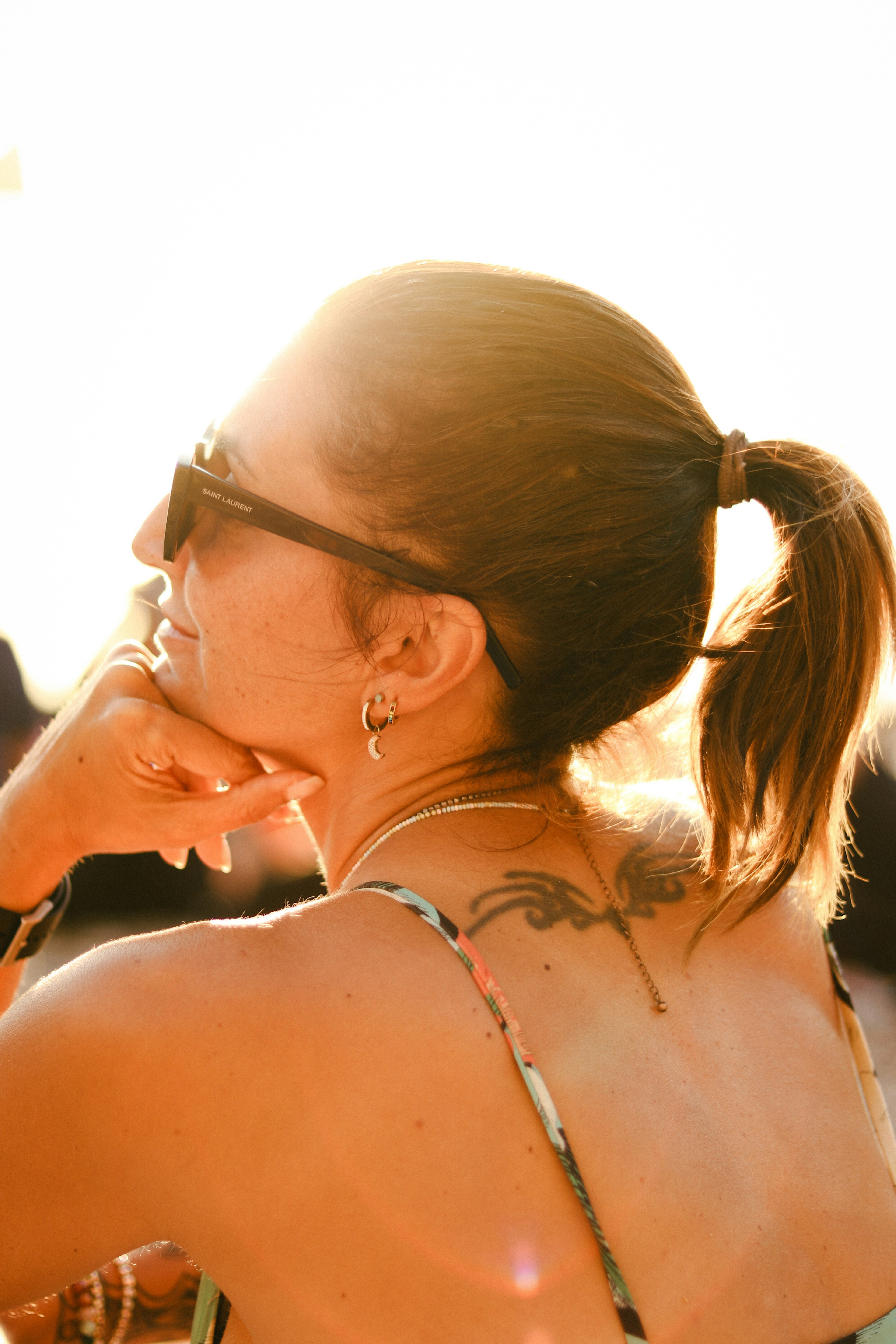 Vista posteriore di una donna che gode della luce del sole indossando occhiali da sole con i capelli raccolti in una coda di cavallo