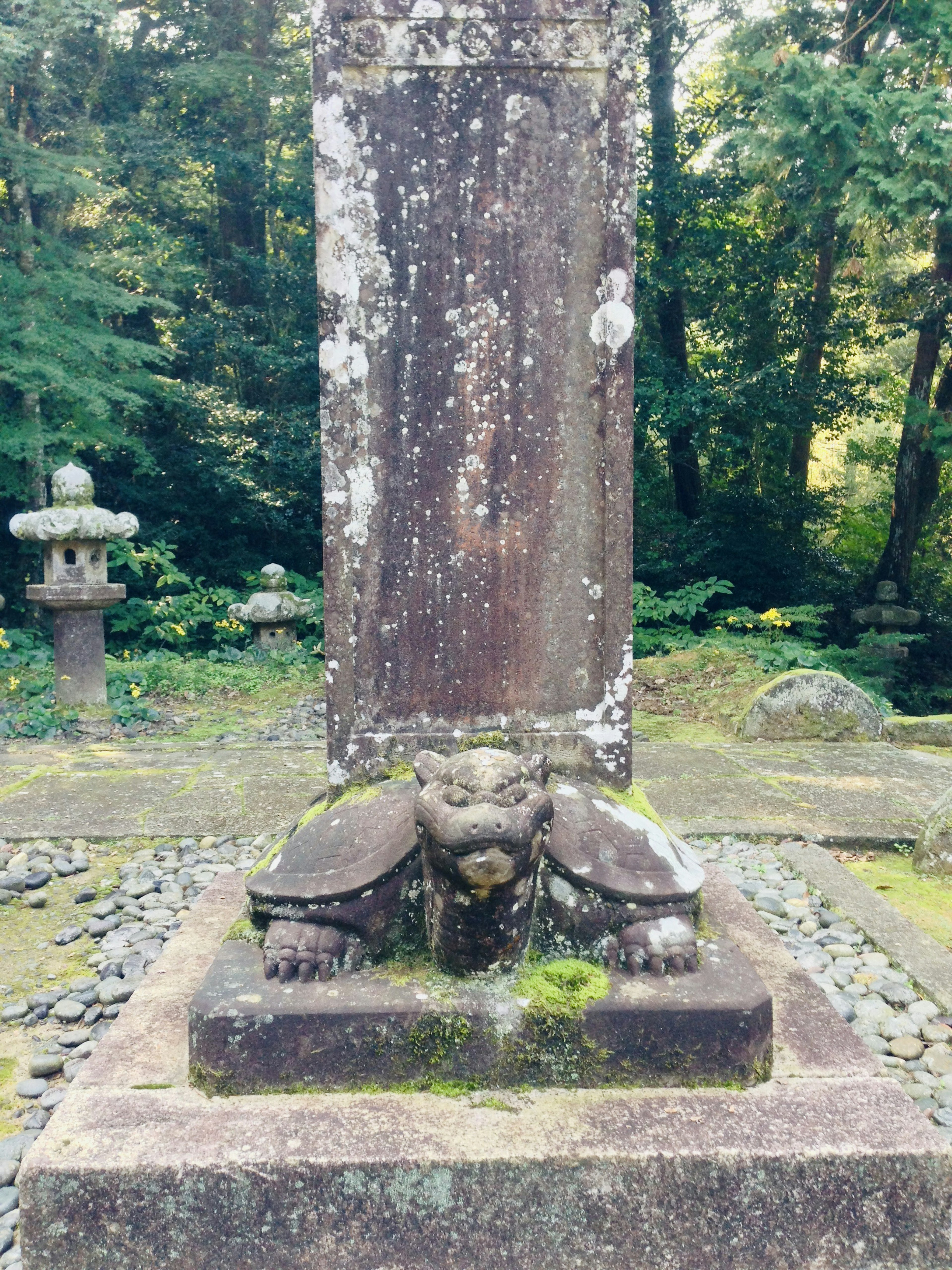 Monument en pierre ancien avec sculpture de lion et base recouverte de mousse