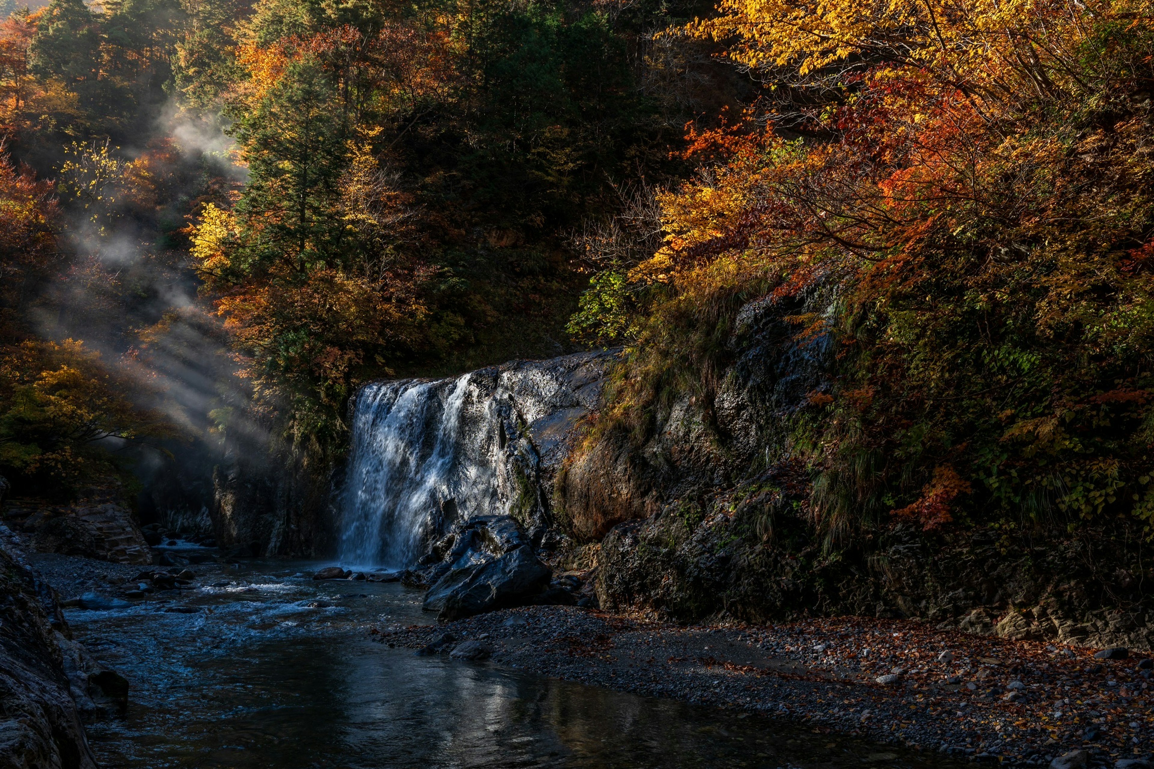 秋の紅葉に囲まれた美しい滝と静かな川の風景