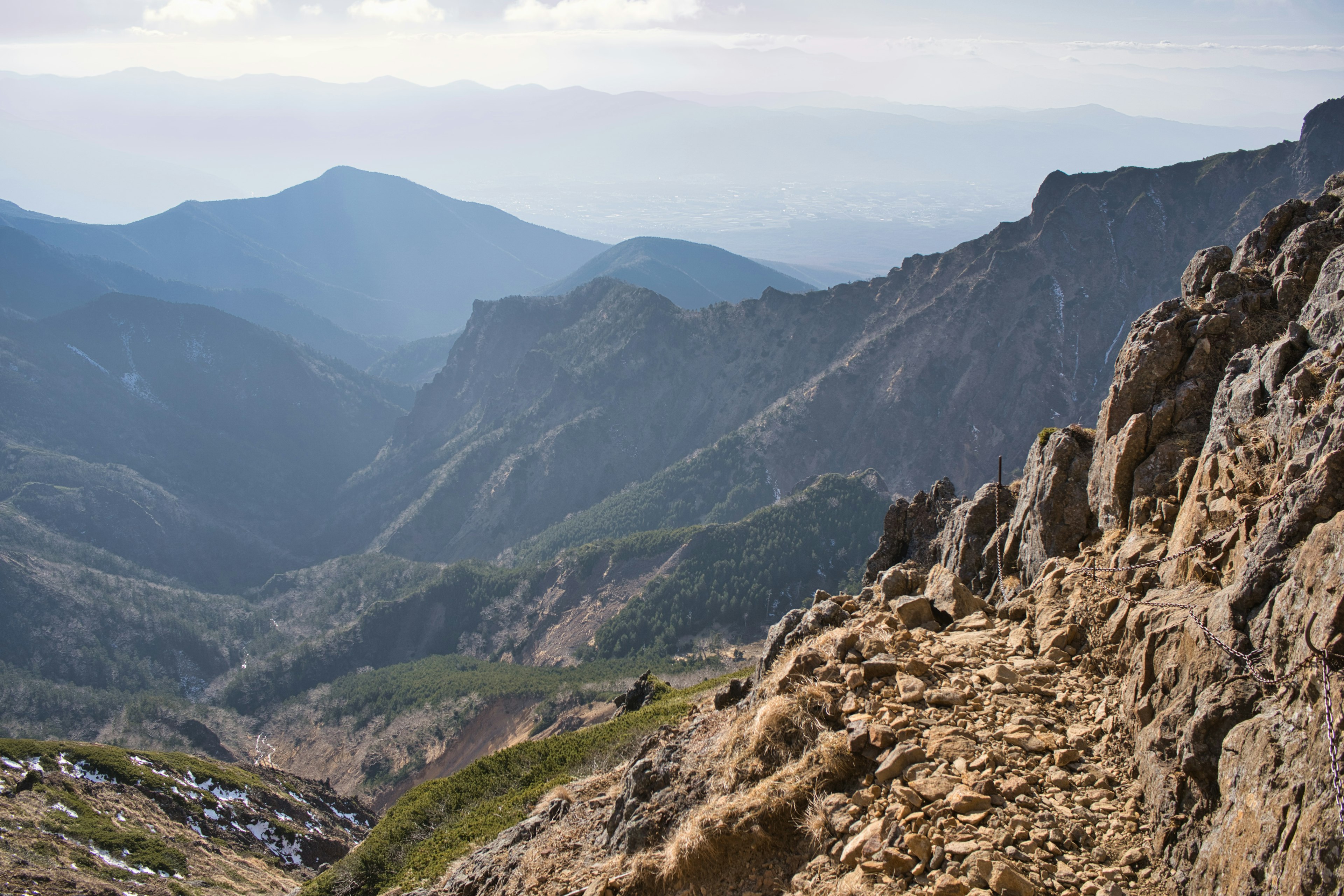 山の風景が広がる景色で、岩の道と緑の斜面が見える