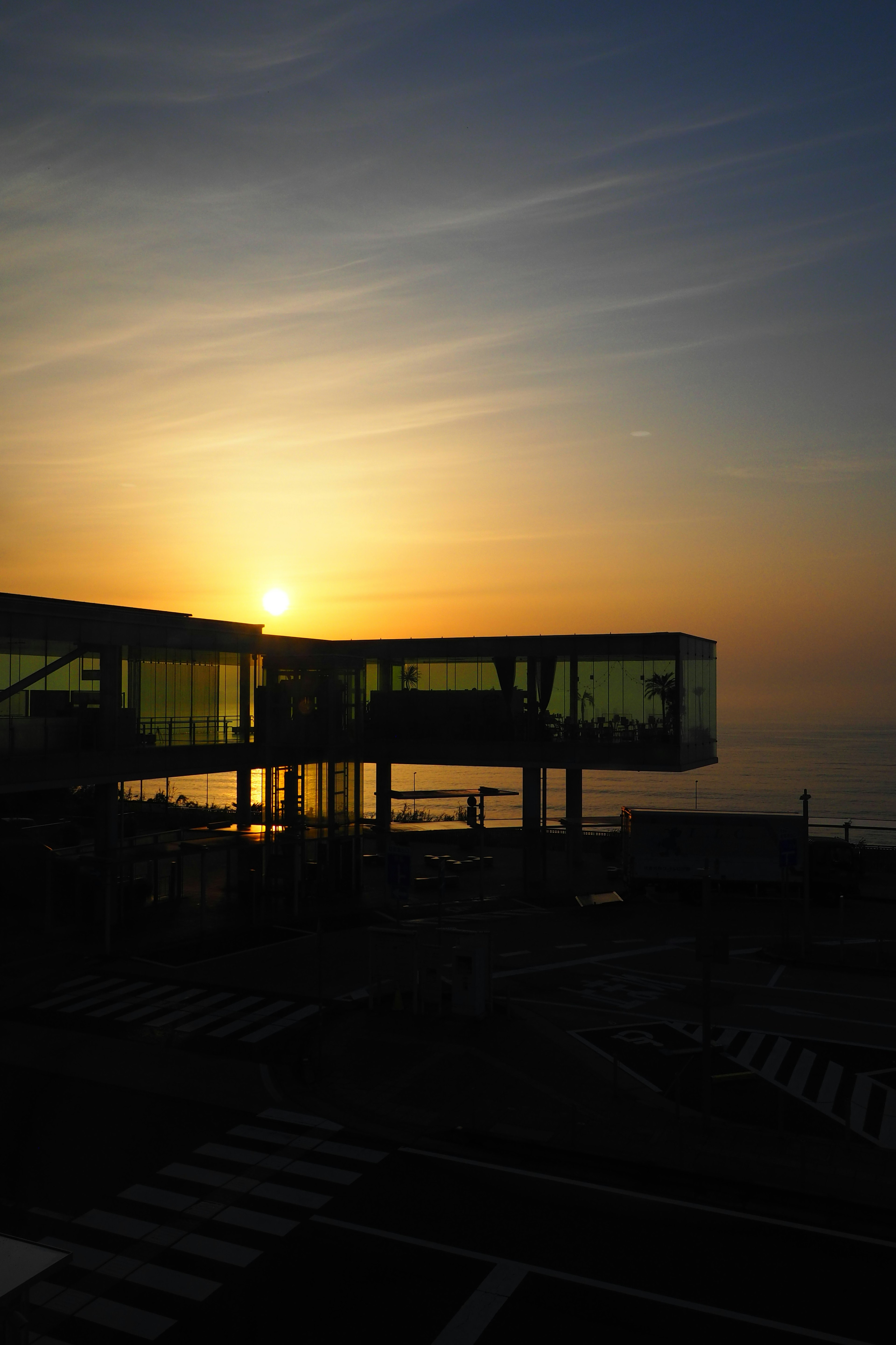 夕日が沈む海の景色とガラス張りの建物