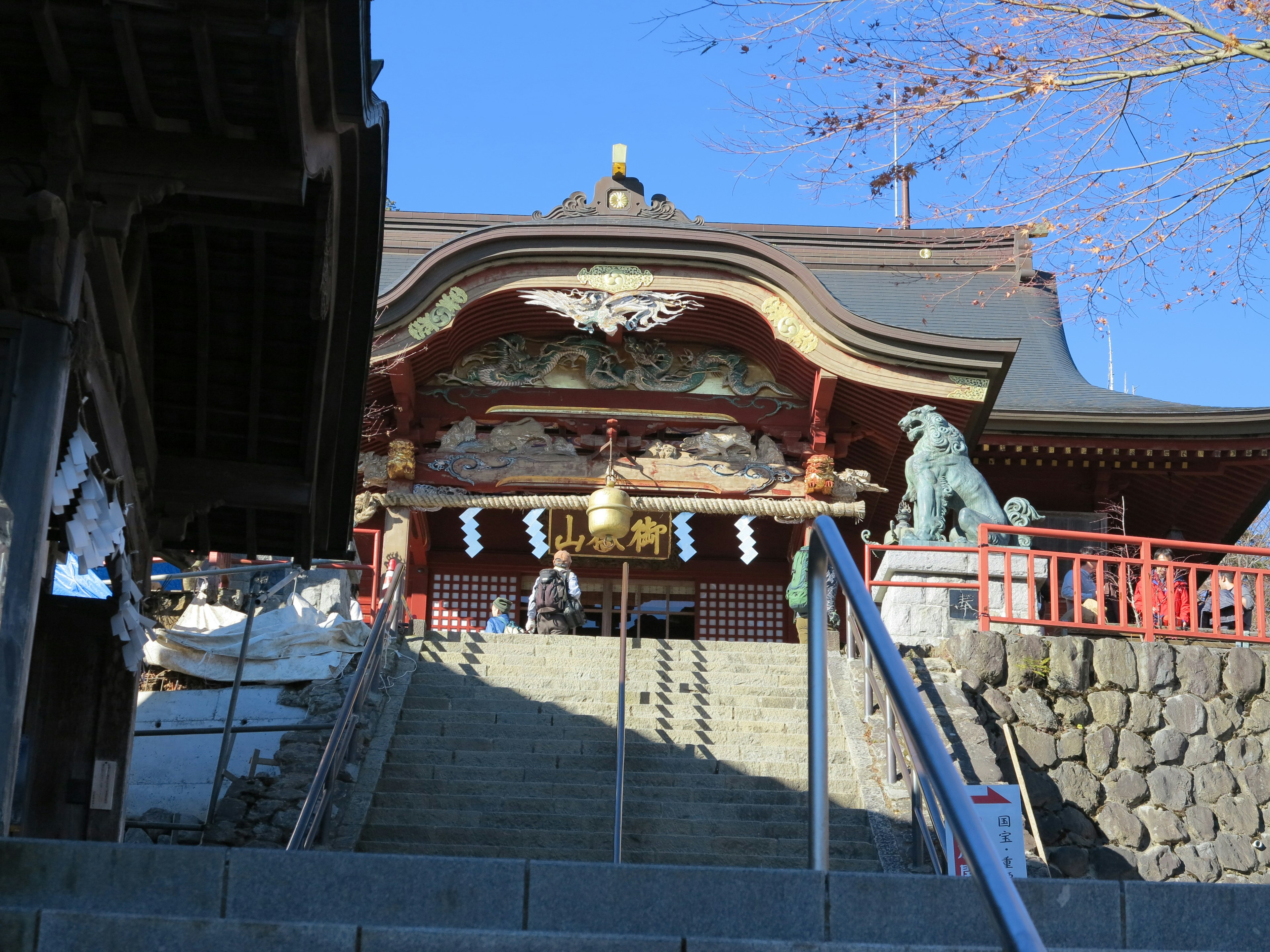 Entrée d'un sanctuaire avec des escaliers rambarde rouge et statues de lions gardiens