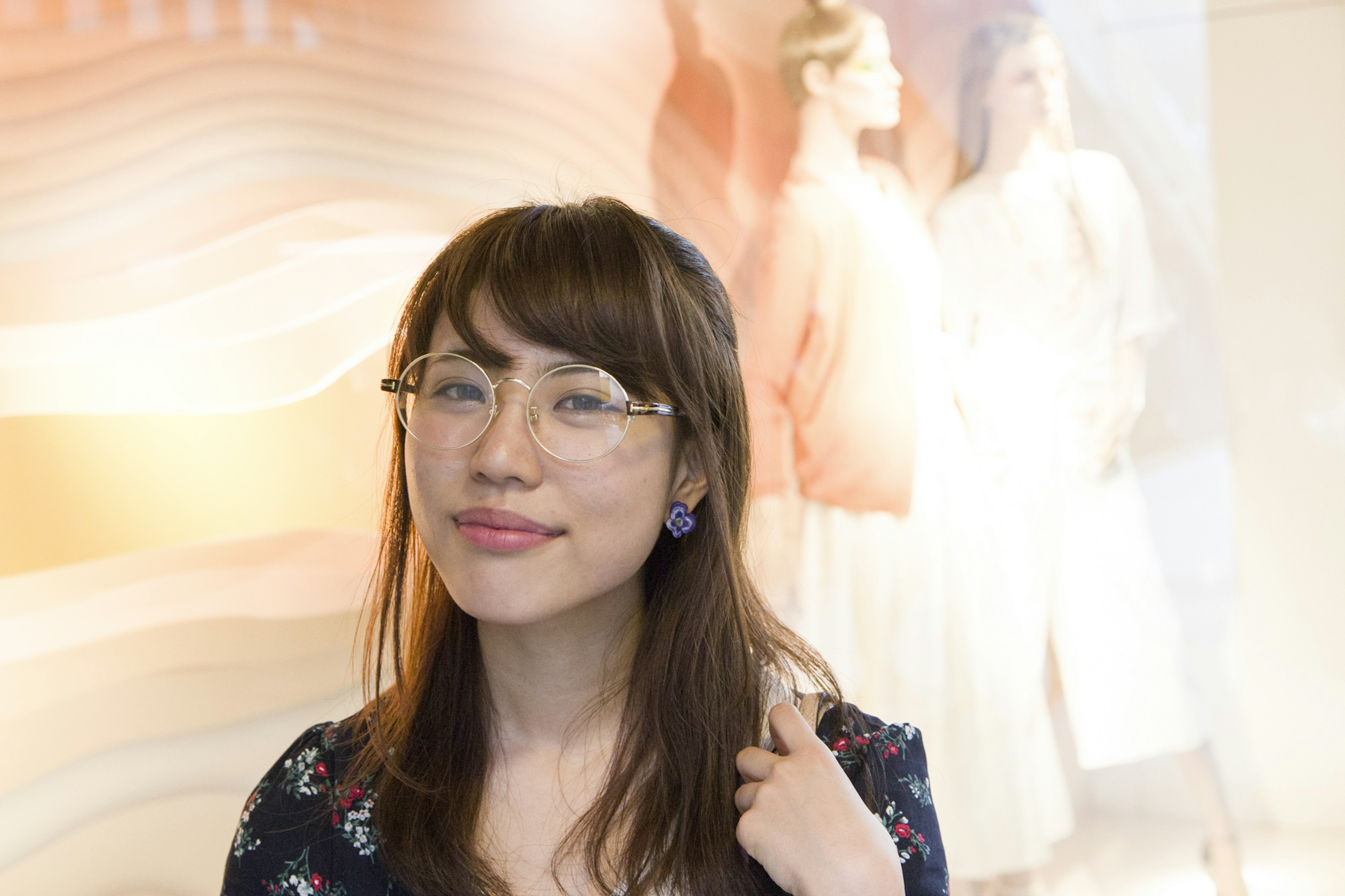 Une femme portant des lunettes souriant avec un affichage de mode en arrière-plan