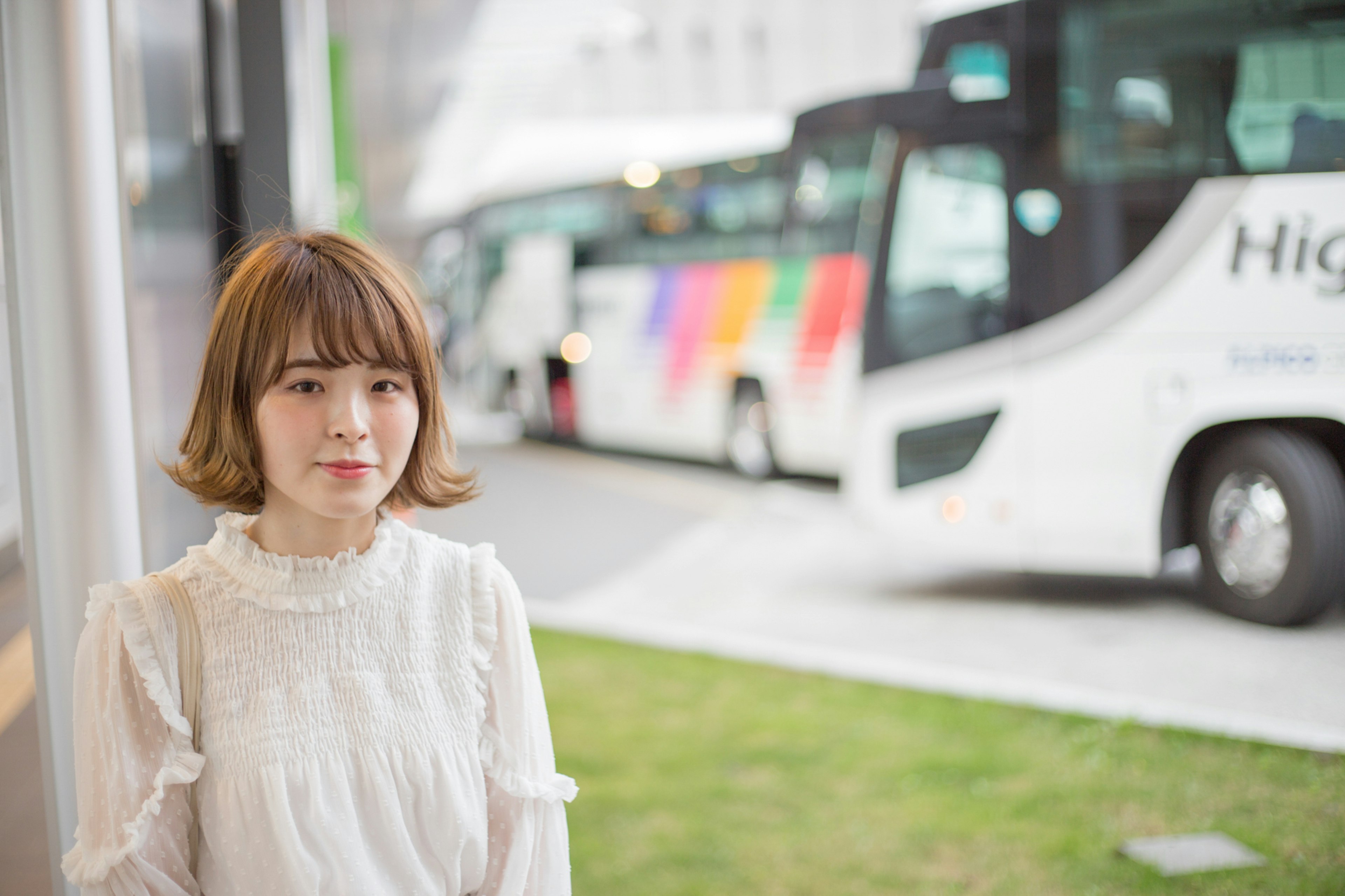 Une femme en blouse blanche se tenant devant des bus