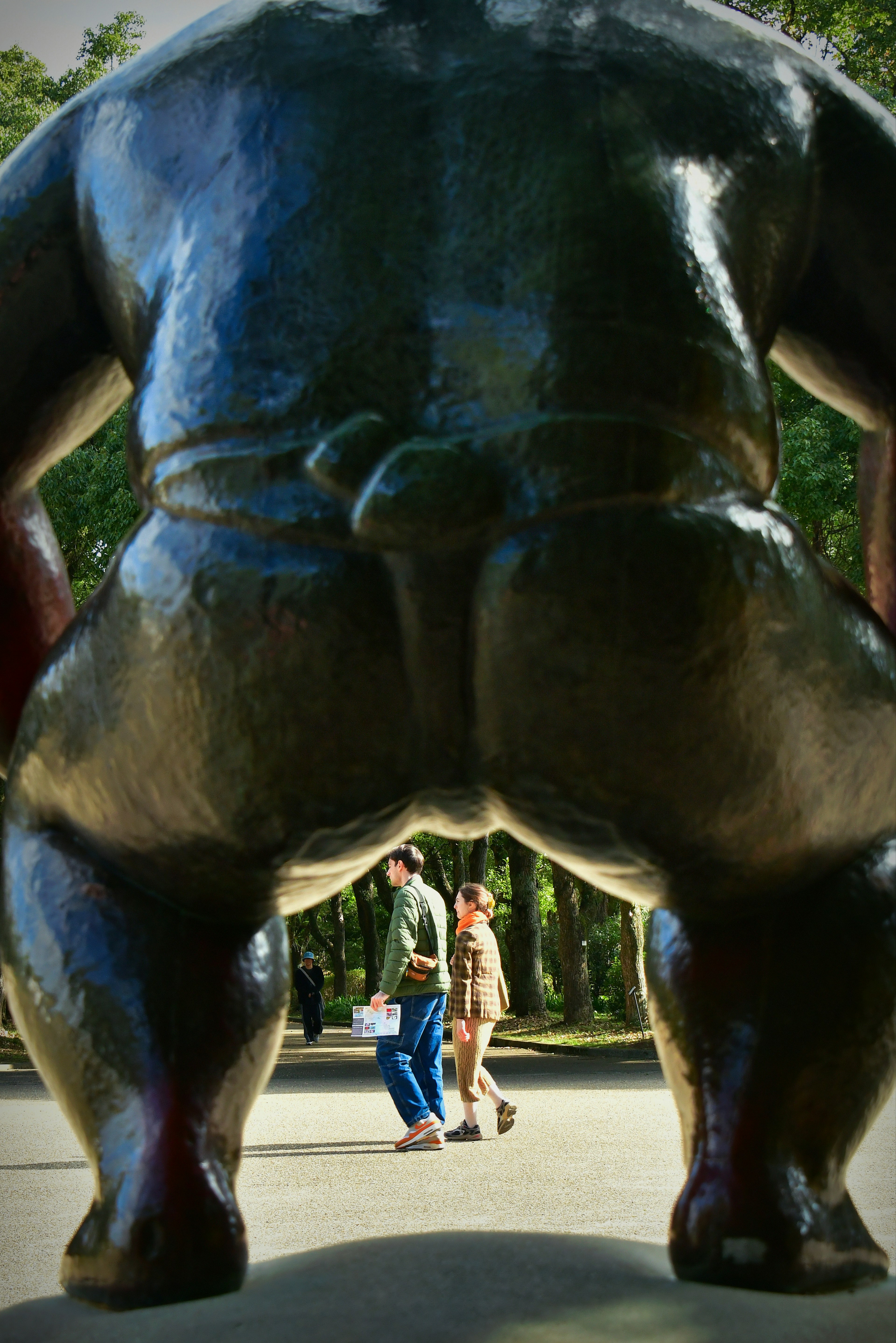 Two people walking in front of a large sculpture viewed from behind