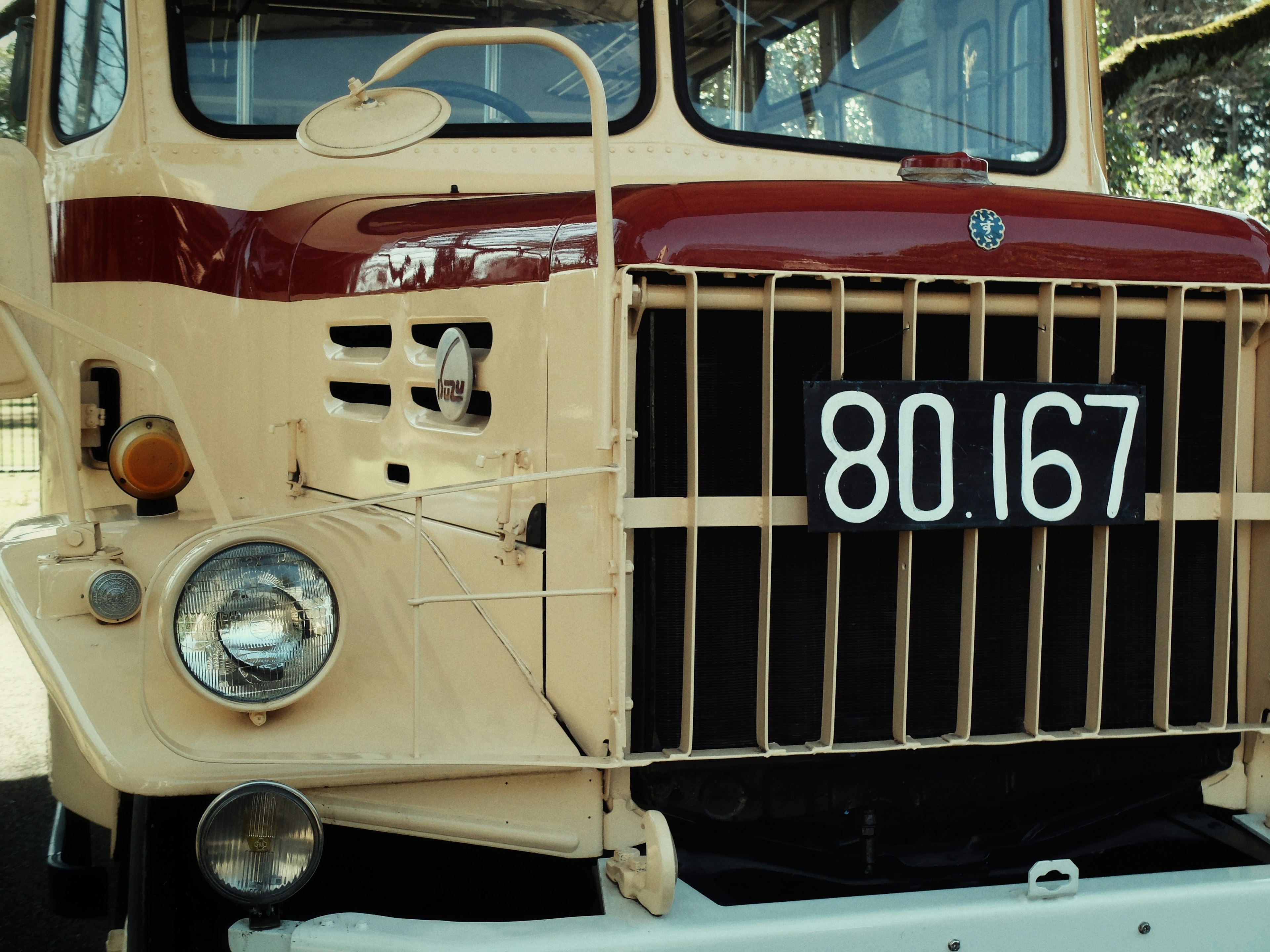 Vue de face d'un vieux camion avec une peinture rouge et crème et une plaque d'immatriculation 80 167