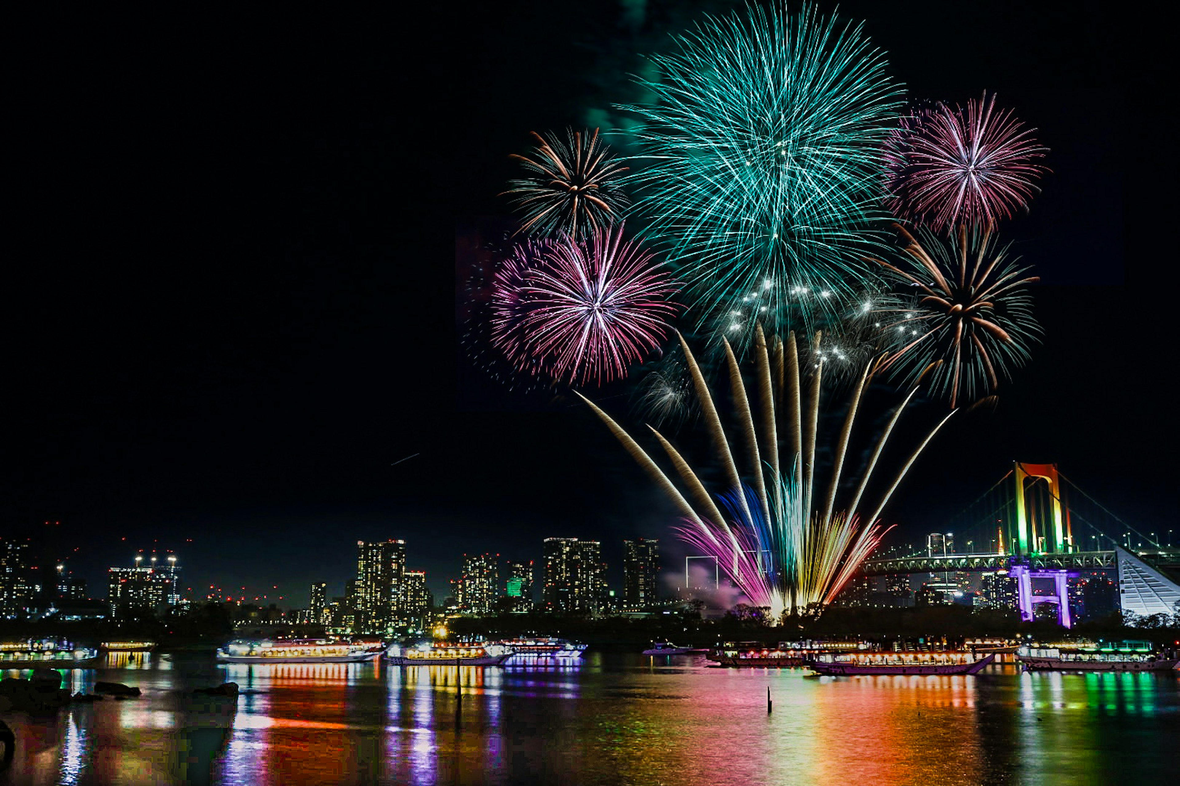 Bunte Feuerwerkshow über der Bucht von Tokio mit der Rainbow Bridge im Hintergrund