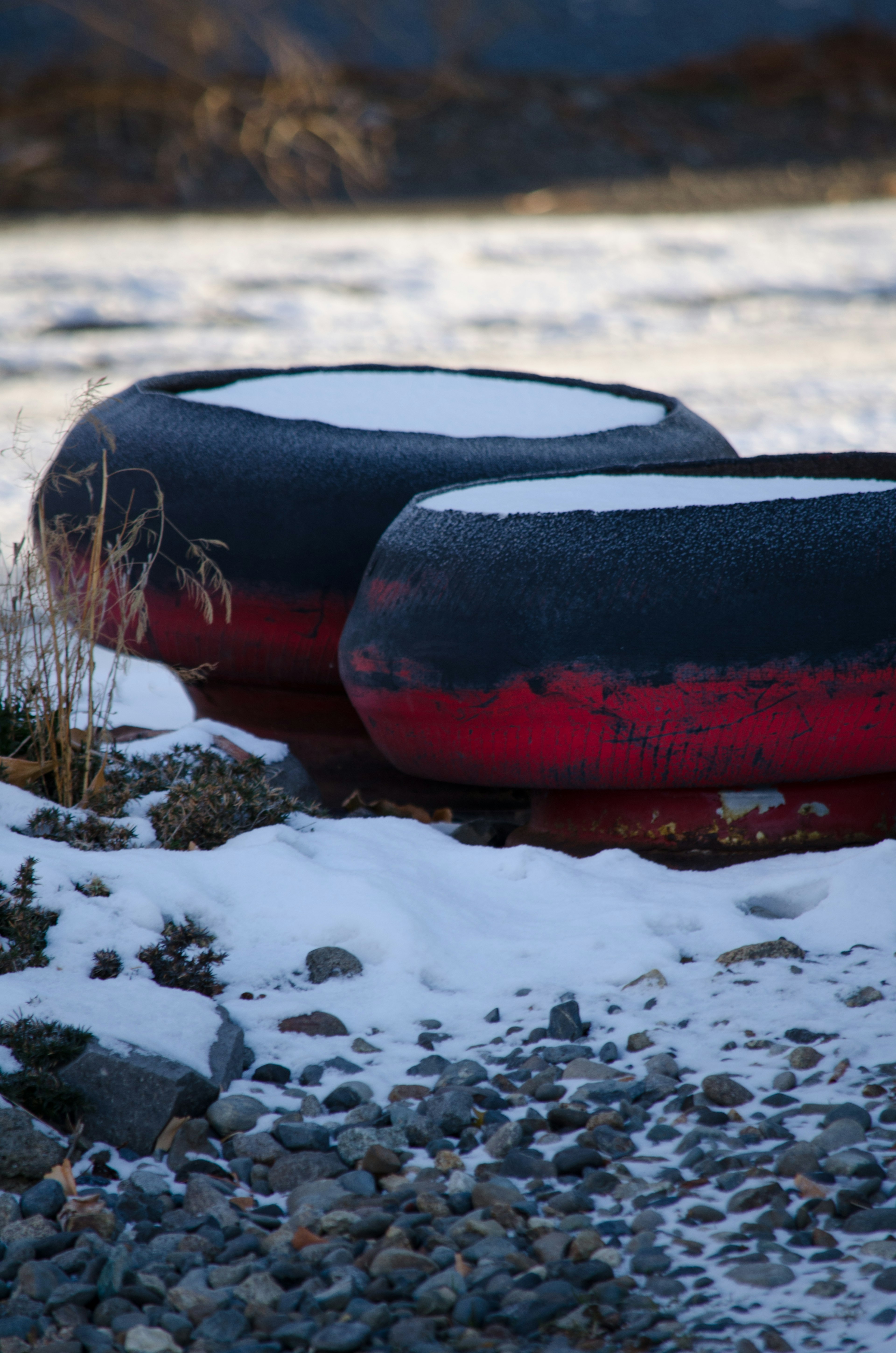 Schwarze und rote Schwimmreifen liegen auf einem mit Schnee bedeckten felsigen Boden