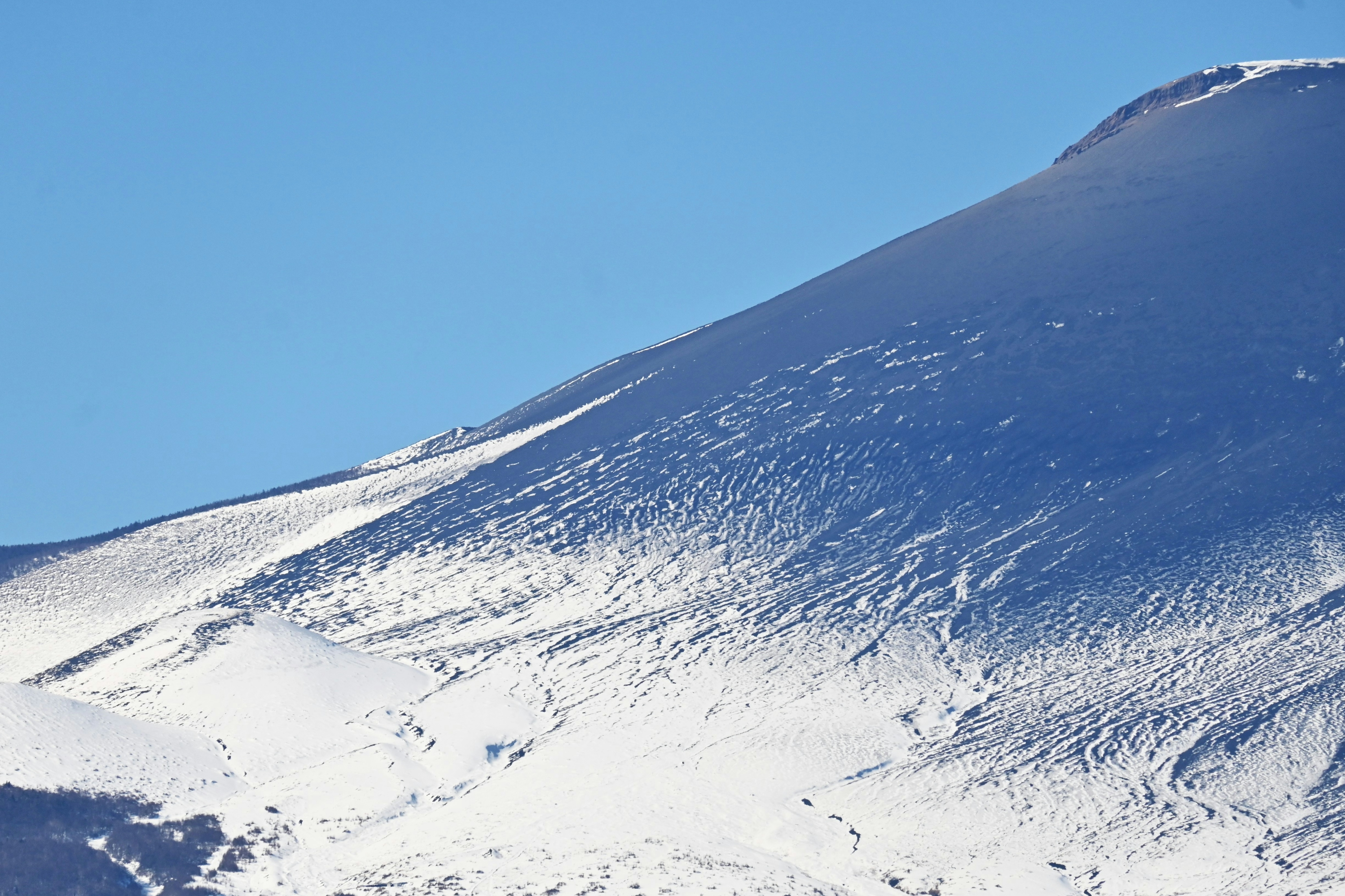 雪に覆われた山の斜面と青い空の風景