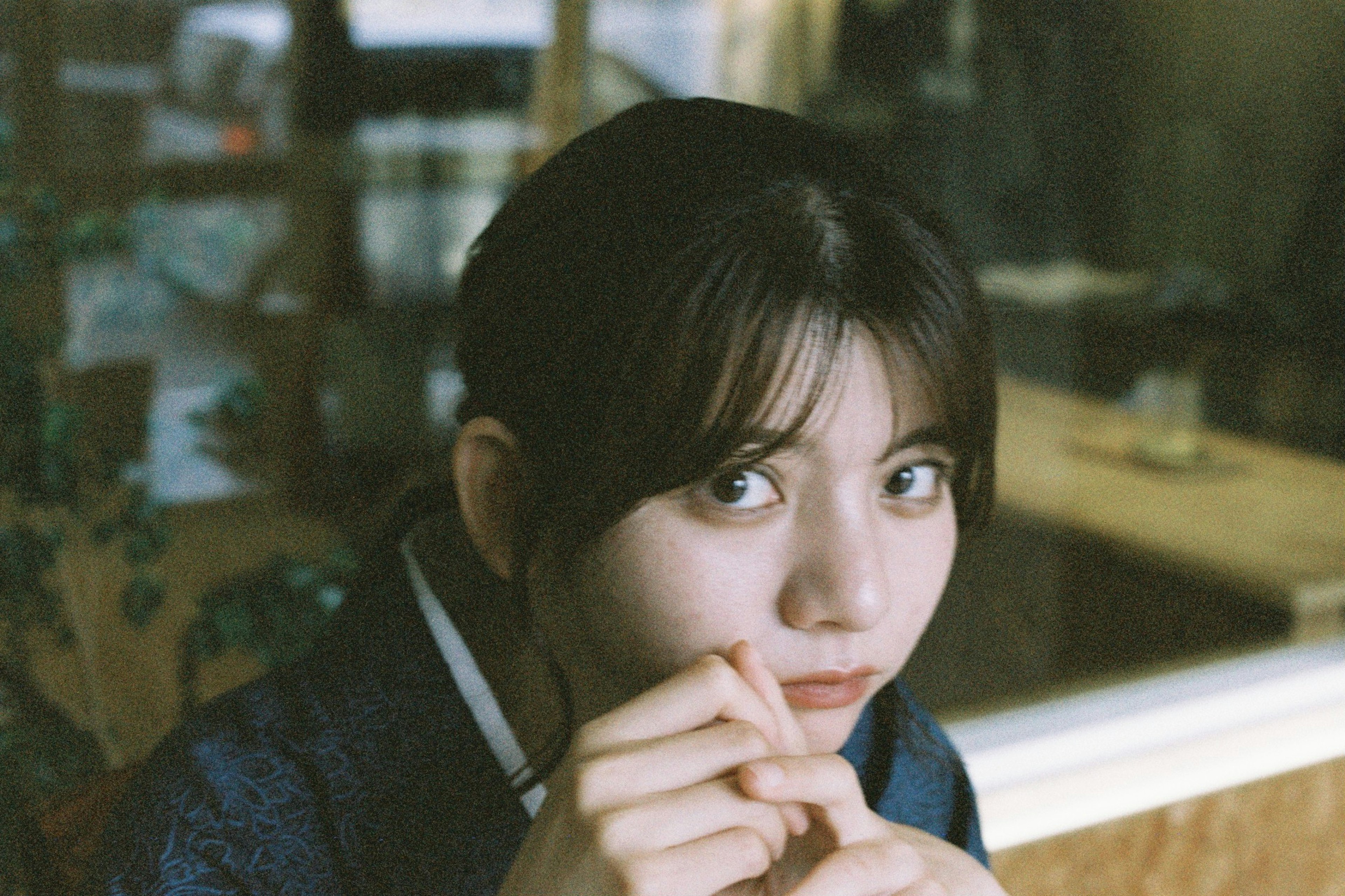 Young woman smiling at a café with straight black hair and large eyes