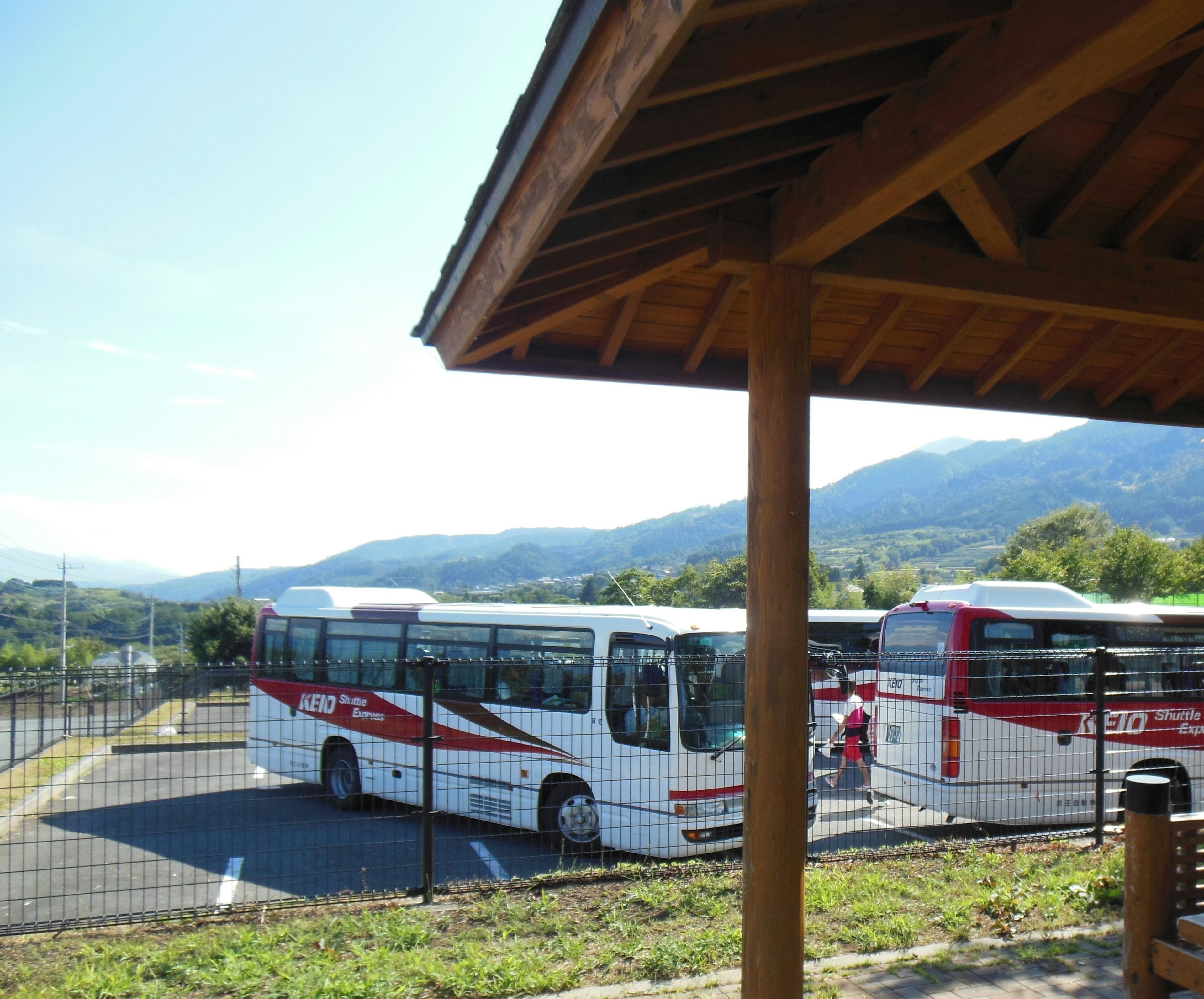 Bus yang diparkir dengan latar belakang pegunungan dan tempat berlindung kayu