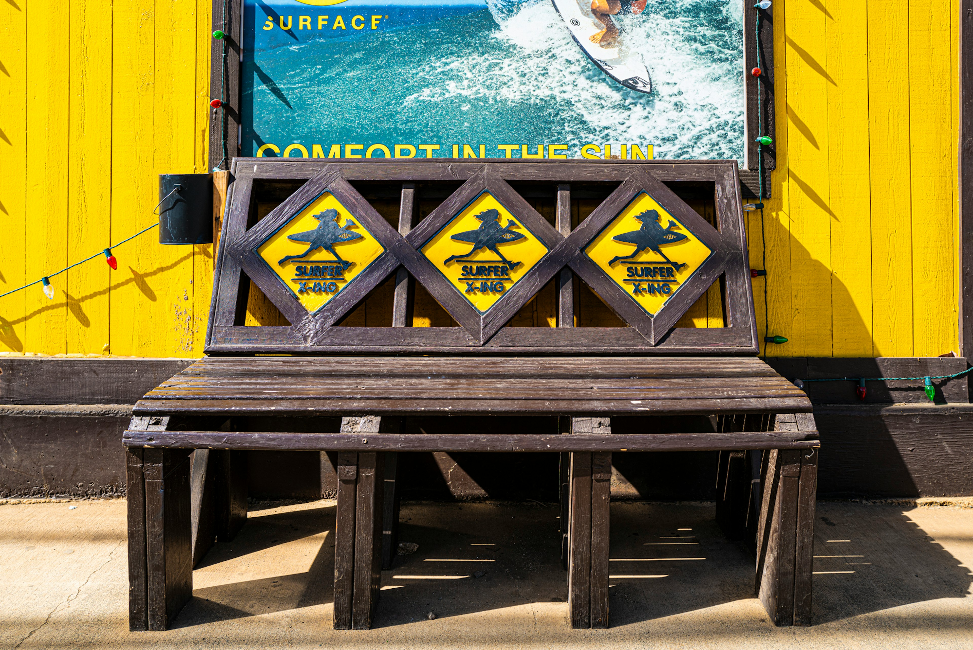 Wooden bench with black designs in front of a yellow wall