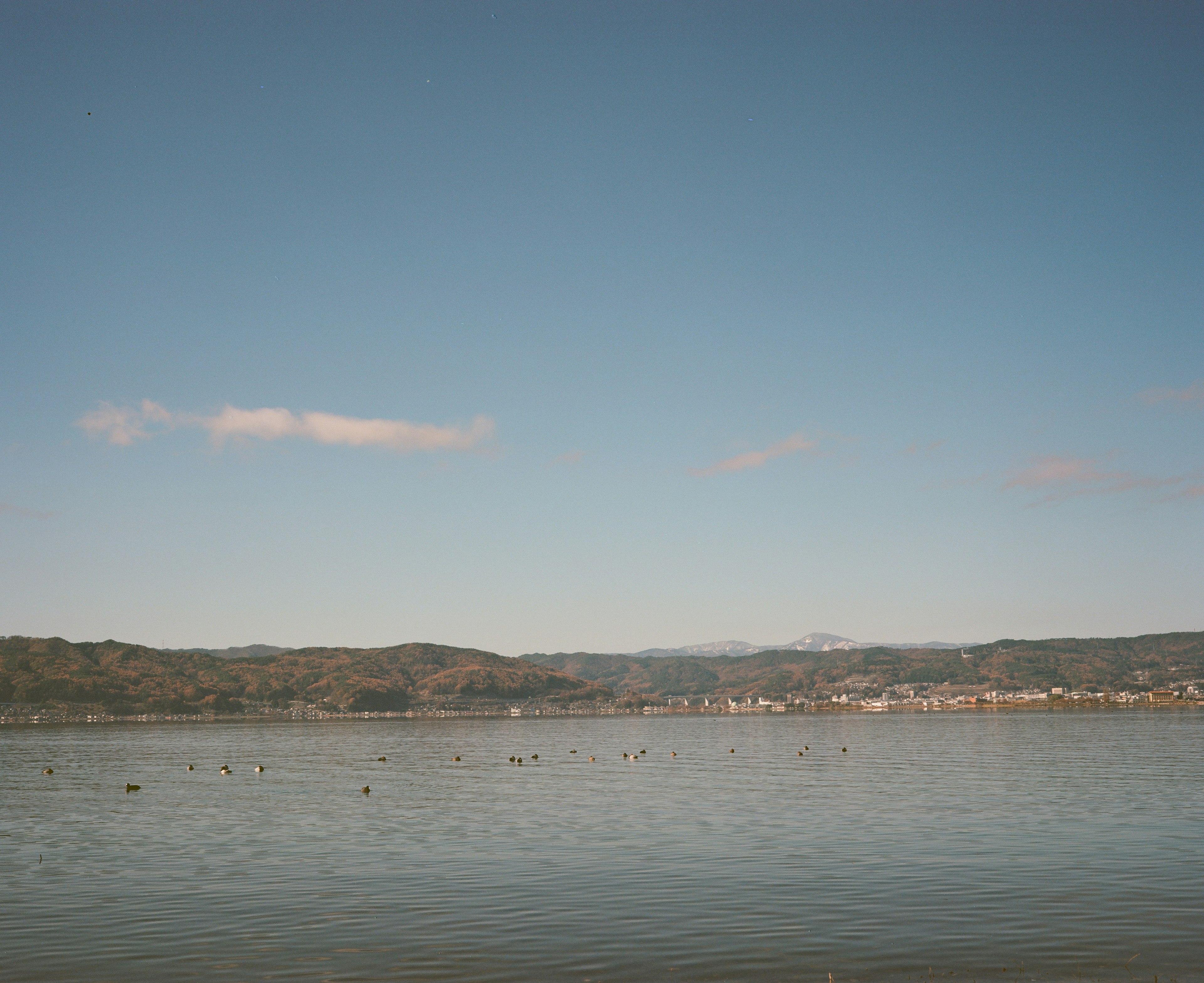 Paysage de surface d'eau calme et ciel bleu avec des montagnes lointaines et une petite ville au bord du lac